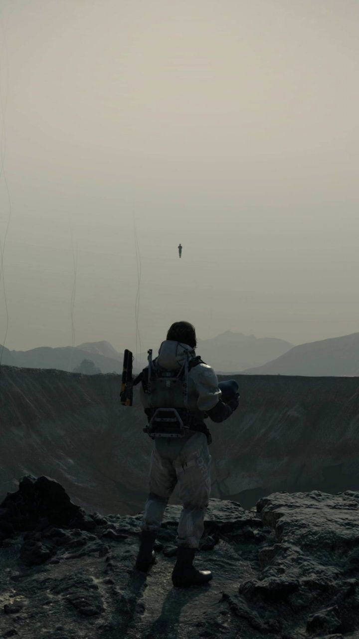 太空人在外星行星上俯瞰霧谷，有漂浮身影 — 死亡擱淺 GIF 壁紙