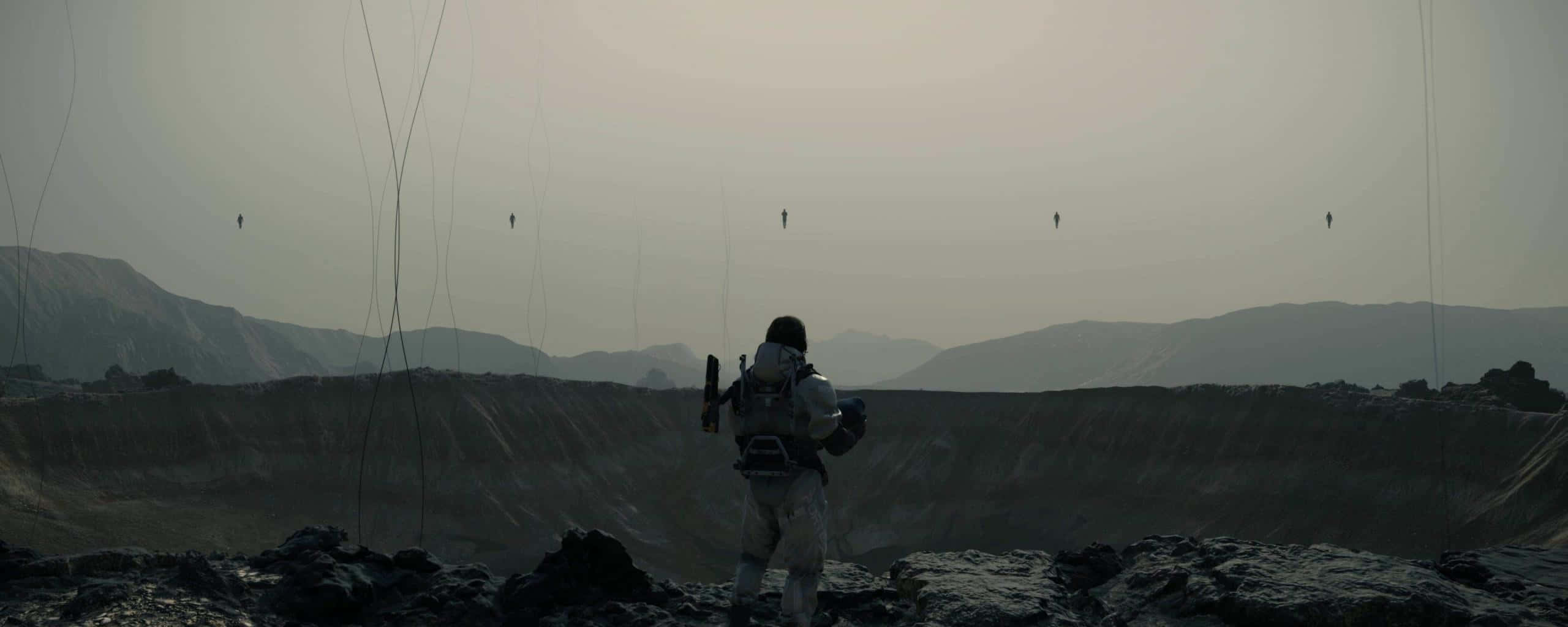 Death Stranding Pc 桌布 壁紙 — 一個孤獨的太空人站在荒蕪的外星景觀中，凝視著遠處漂浮的人影，背景是朦朧的天空。