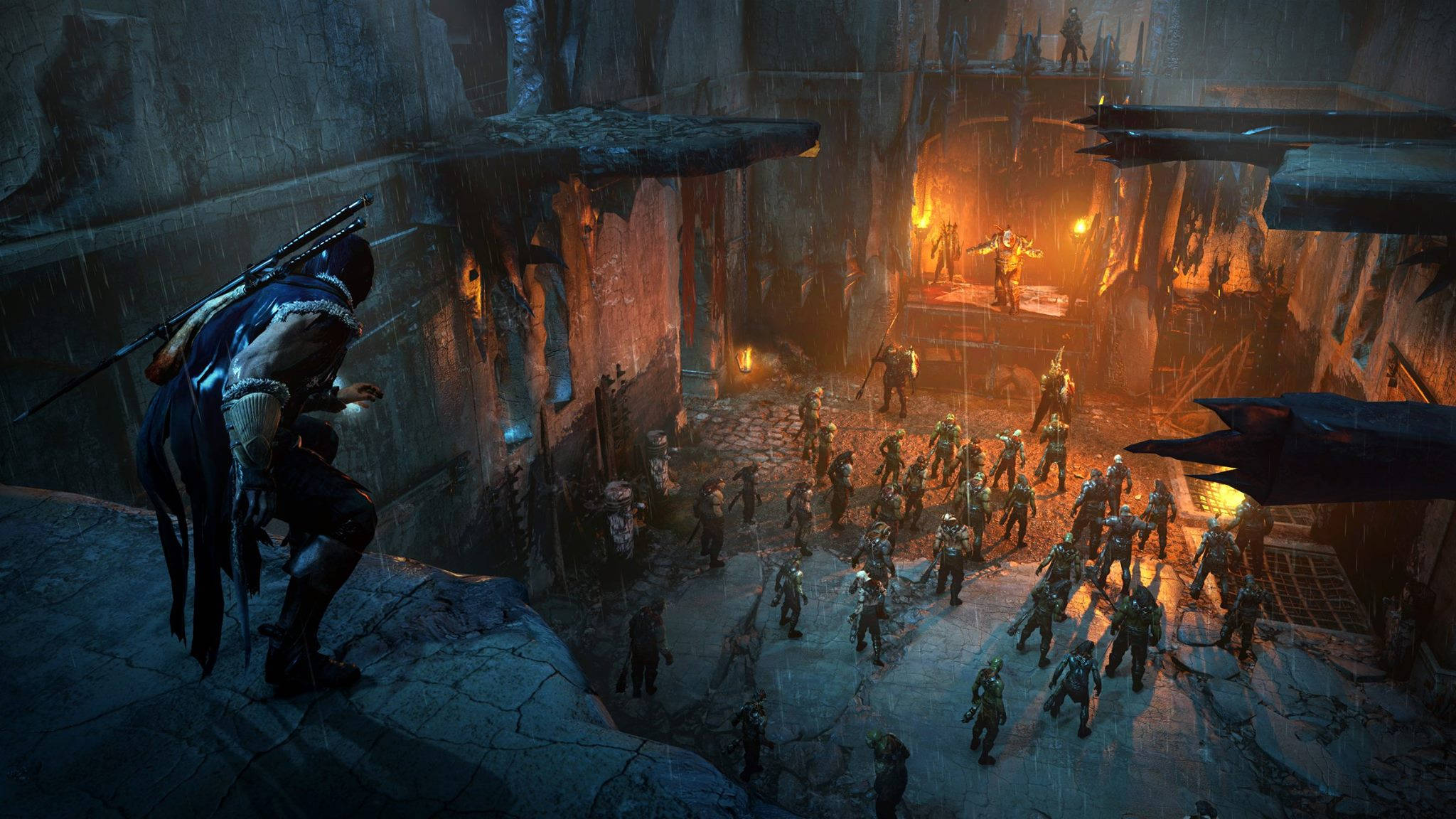 shadow of mordor 4K 桌布 壁紙 — 一個孤獨的戰士手持劍，站在懸崖上俯瞰一個被雨水浸透的洞穴，那裡的人群聚集在一個熾熱的祭壇周圍。