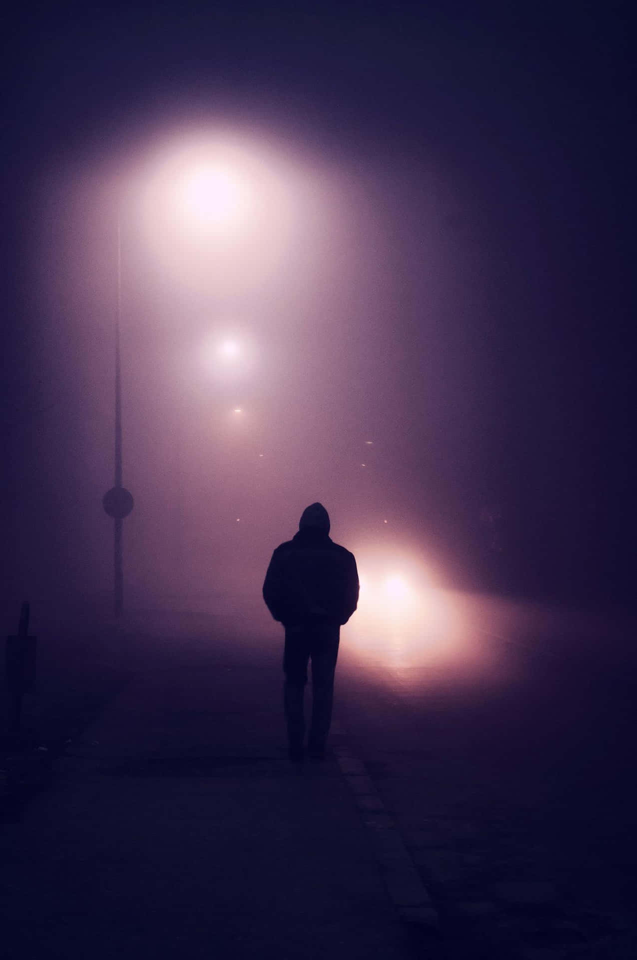 在發光的燈光下，夜間霧氣瀰漫的城市街道上獨自行走的人的剪影。 — 單身男孩 壁紙