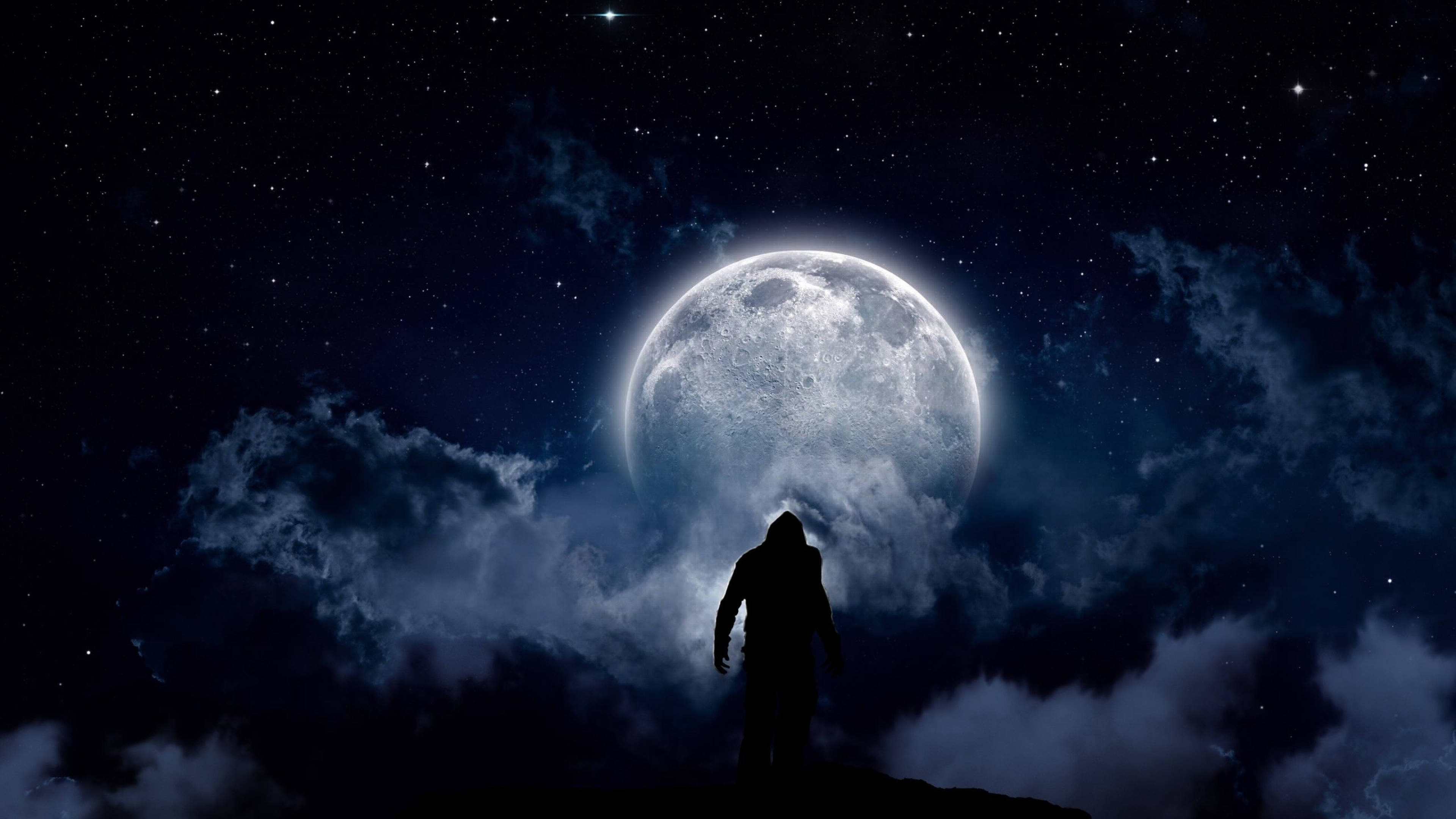 moonlight 4K 桌布 壁紙 — 一個孤獨的戴帽人影站在懸崖上，襯托著一個巨大發光的月亮，周圍環繞著旋轉的雲層和星星。
