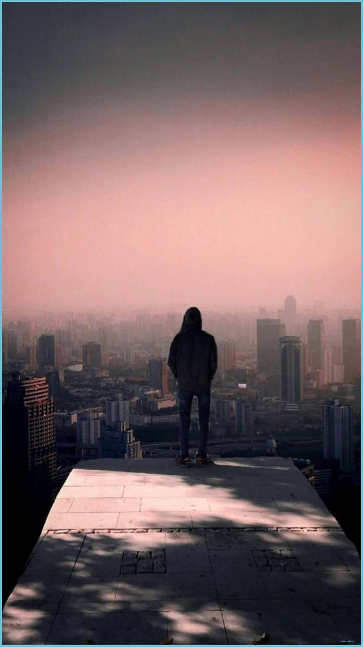 Alone Boy 桌布 壁紙 — 一個孤獨的戴帽人站在屋頂上，俯瞰著籠罩在柔和粉紅與灰色暮色中的朦朧城市景觀。