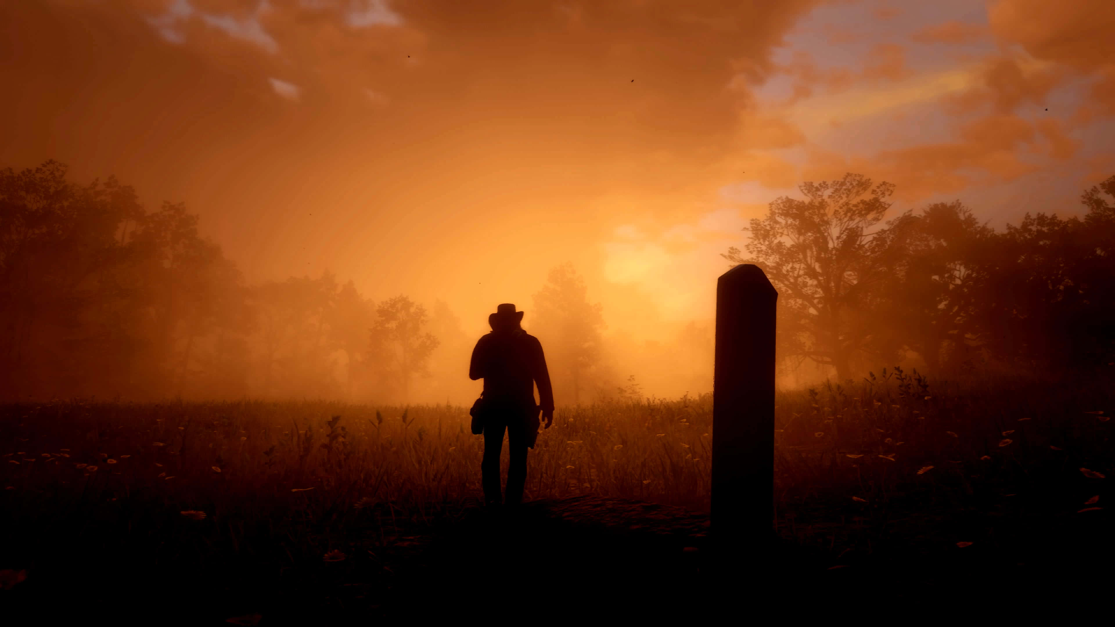 Red Dead Redemption 4K 桌布 壁紙 — 一個孤獨的牛仔剪影站在墓碑旁邊，身處被溫暖橙色夕陽籠罩的霧氣田野中。