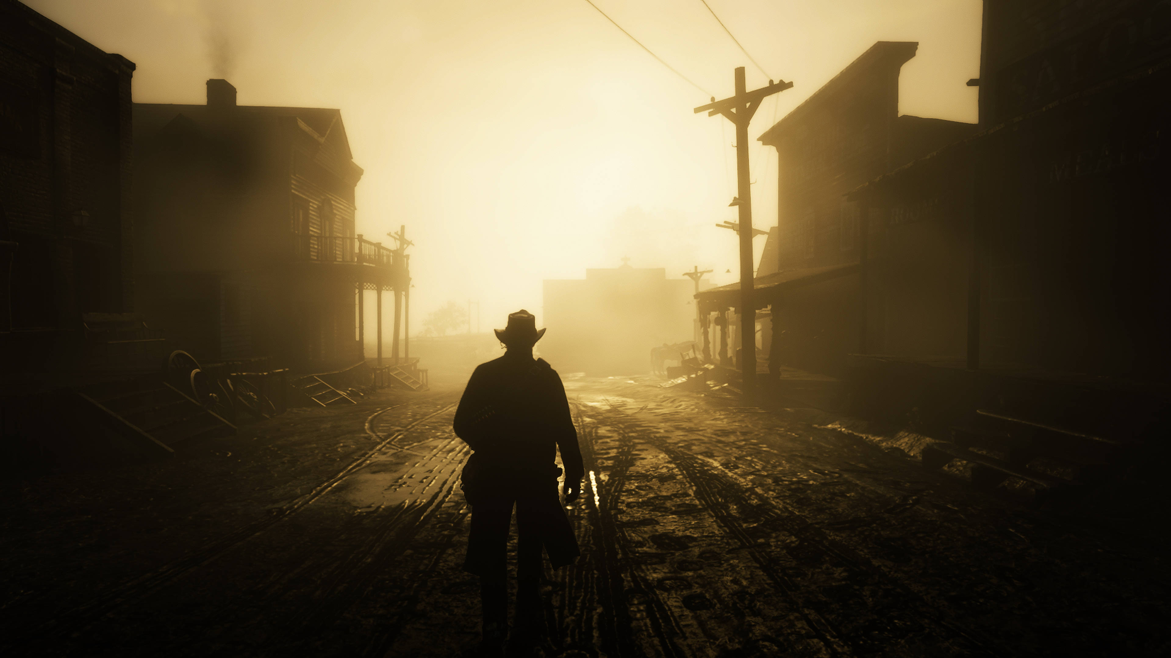 Red Dead Redemtion 2 桌布 壁紙 — 一個孤獨的牛仔在日出時分走在一條霧氣瀰漫、塵土飛揚的鬼城街道上，建築物在金色光芒中呈現剪影。