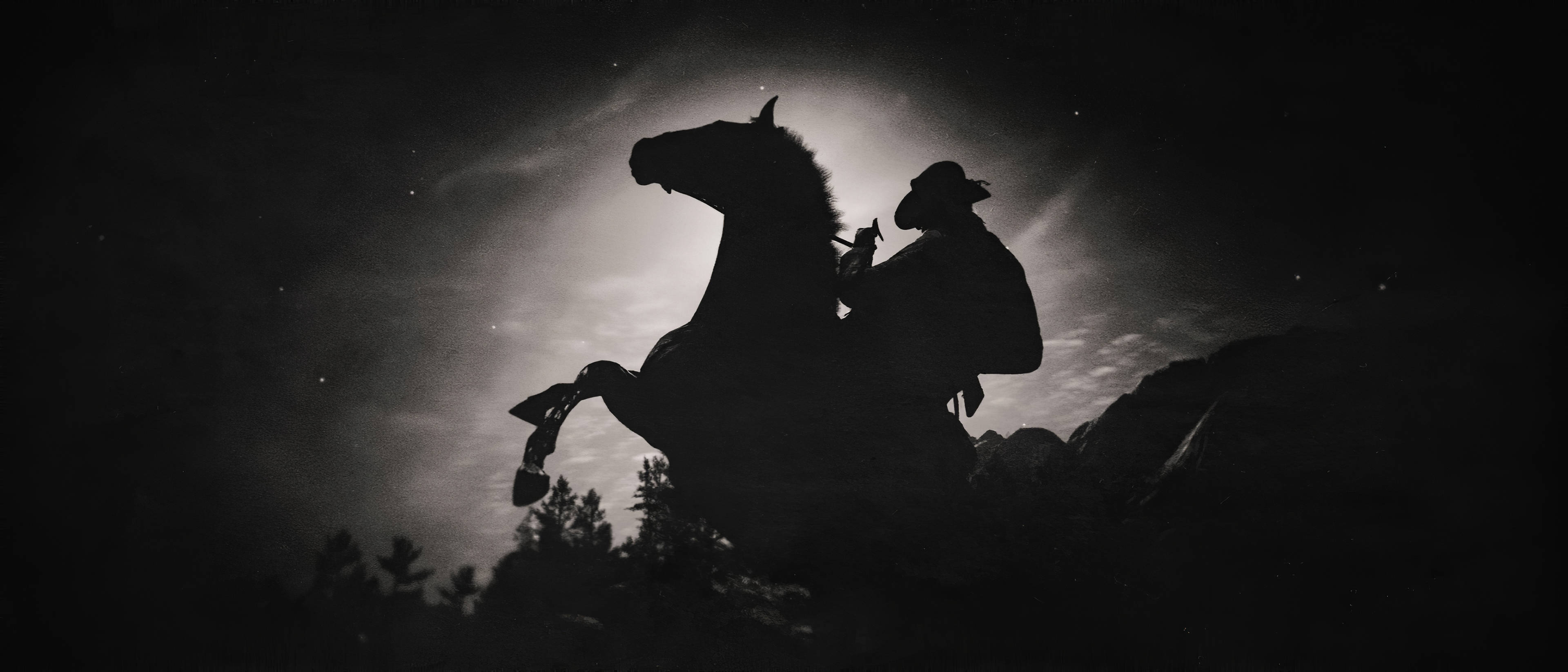 Red Dead Redemtion 2 桌布 壁紙 — 一個孤獨的牛仔騎著一匹後腿站立的馬，以剪影形式映襯著繁星點點的夜空和發光的雲朵。