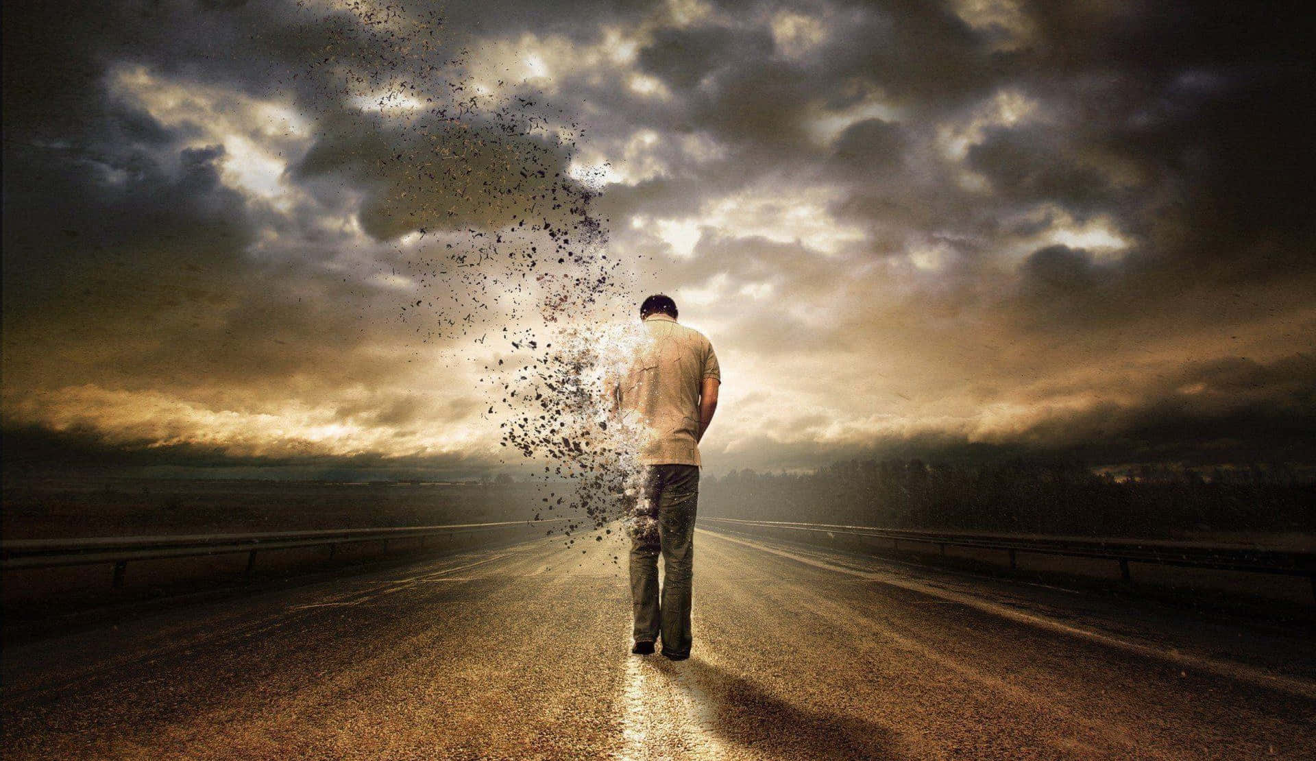 Alone 桌布 壁紙 — 一個孤獨的男人站在空無一人的高速公路上，他的身體在戲劇性的暴風雨天空下分解成粒子。