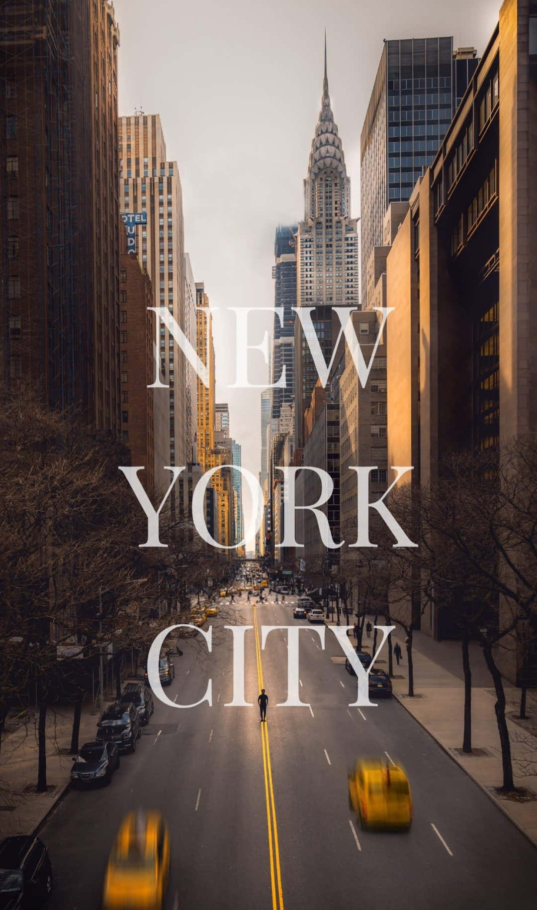 iPhone Xs New York 桌布 壁紙 — 一個孤獨的行人走在陽光明媚的紐約市街道上，兩旁是高聳的摩天大樓和黃色的計程車。