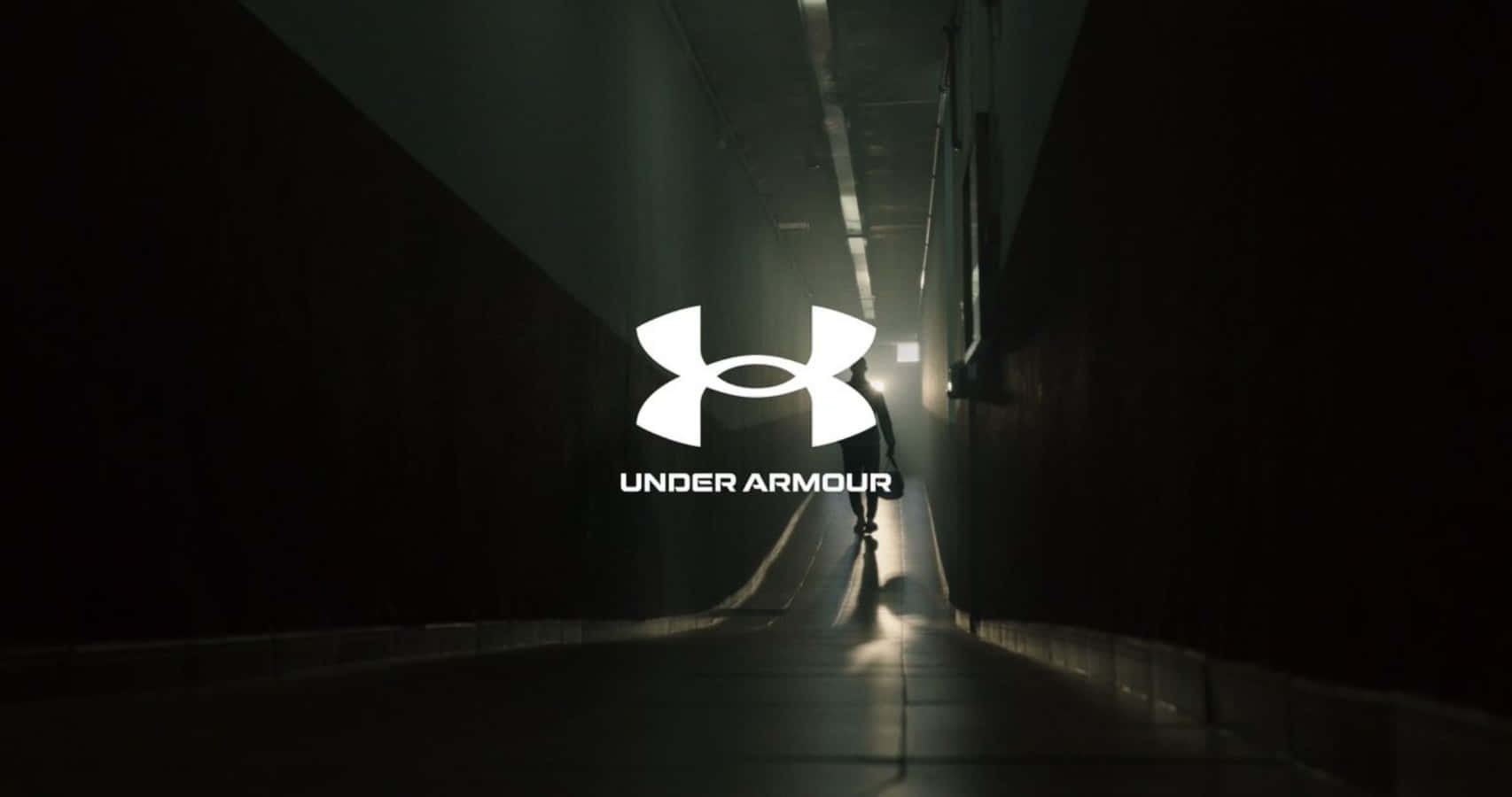 Under Armour 桌布 壁紙 — 一個孤獨的跑者在昏暗的隧道中形成剪影，前景中央有發光的Under Armour標誌。