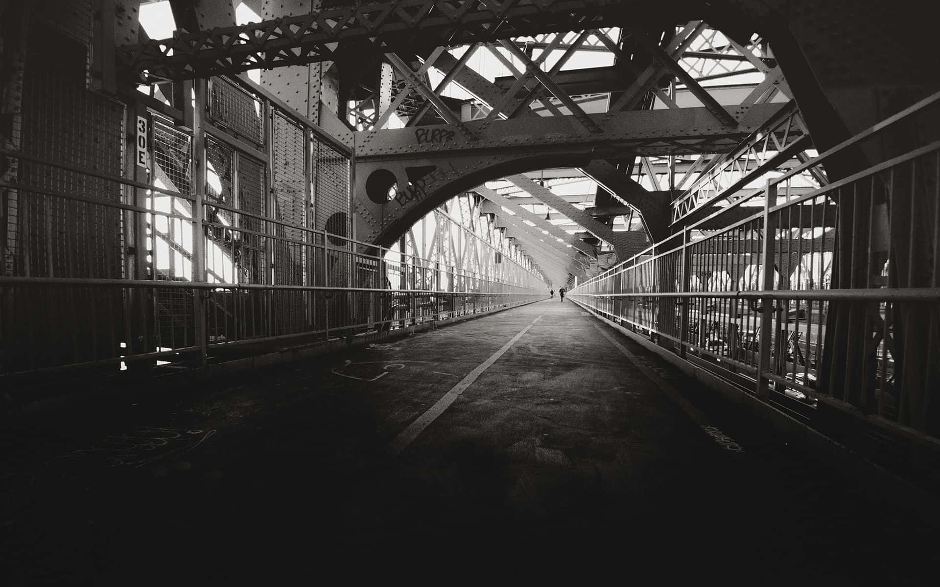 Black And White Architecture 桌布 壁紙 — 一個孤獨的身影在單色調中，沿著一條長長的陰影金屬橋，走在複雜的鋼桁架結構下。