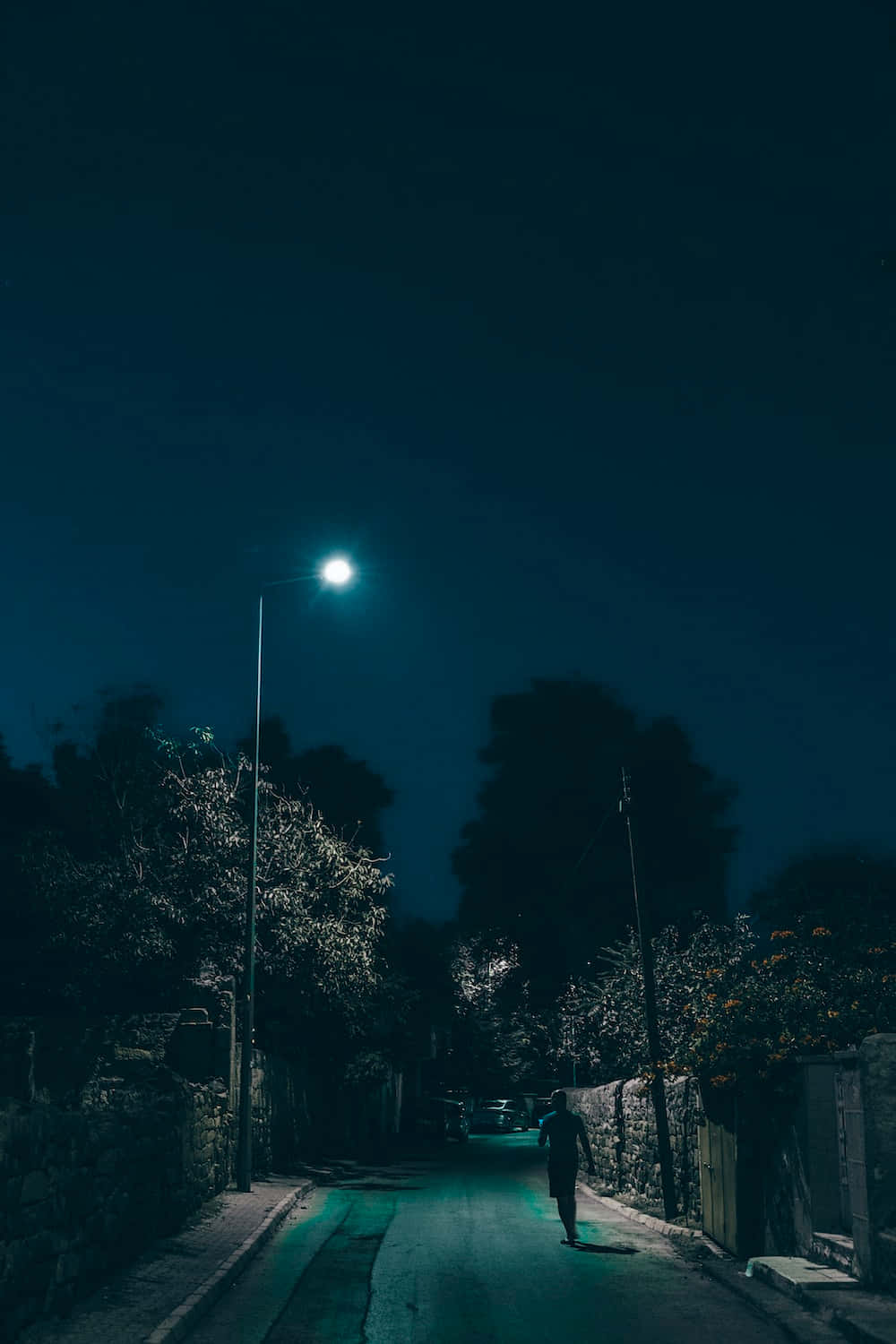 夜晚 桌布 壁紙 — 一個孤獨的身影在夜晚沿著狹窄的街道行走，在一盞路燈的照耀下投下長長的影子。