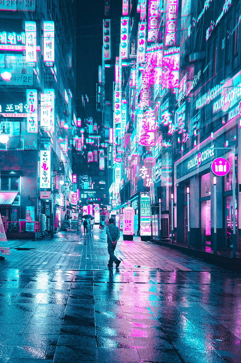 Screen 桌布 壁紙 — 一個孤獨的身影在夜晚沿著被雨水浸濕、霓虹燈閃爍的小巷行走，周圍是發光的粉紅色和青色招牌，倒映在濕漉漉的人行道上。