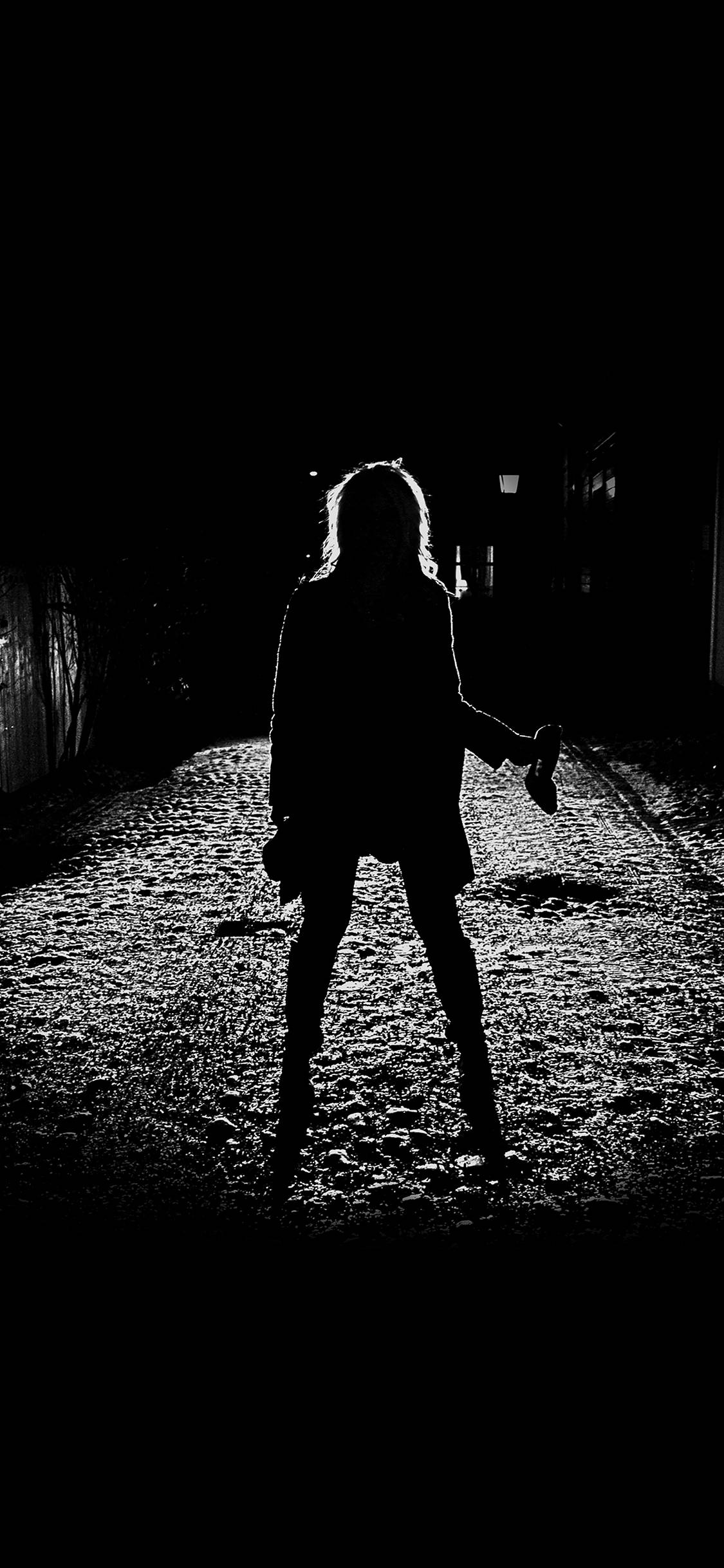 Creepy Aesthetic 桌布 壁紙 — 一個孤獨的身影在夜晚狹窄的小巷中，沐浴在一束光線下，形成鮮明的剪影。