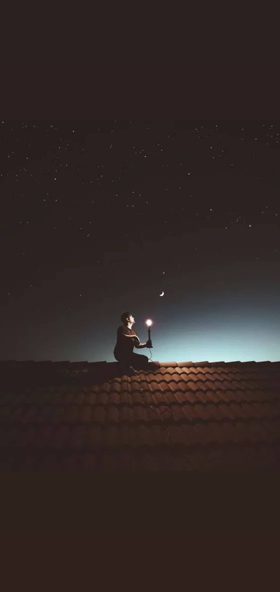 Single 桌布 壁紙 — 一個孤獨的身影在夜晚跪在瓦屋頂上，在繁星點點的天空和彎月下舉著發光的燈籠。