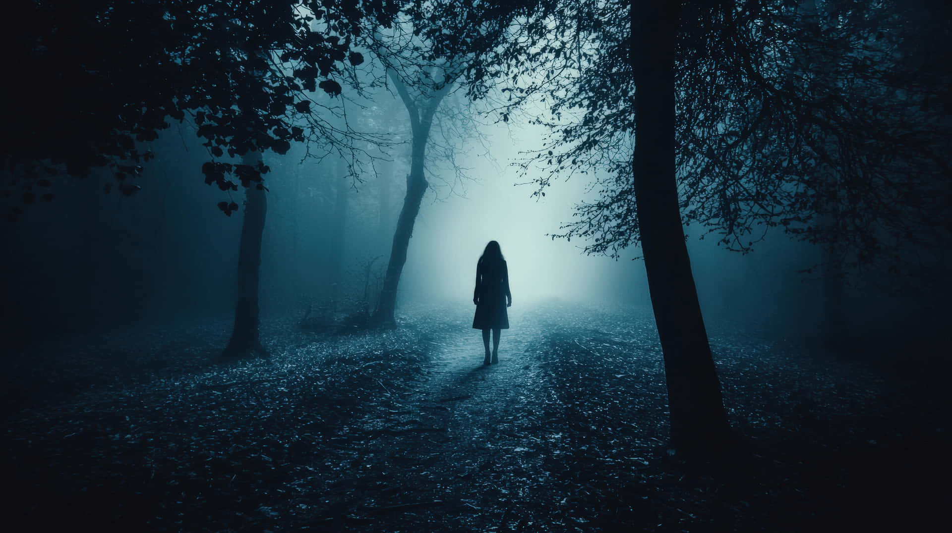 Silhouette of a woman walking in a mysterious foggy forest at night. 壁紙 — 一個孤獨的身影在寒冷的藍光下，沿著被黑暗樹木環繞的霧濛濛森林小徑行走。