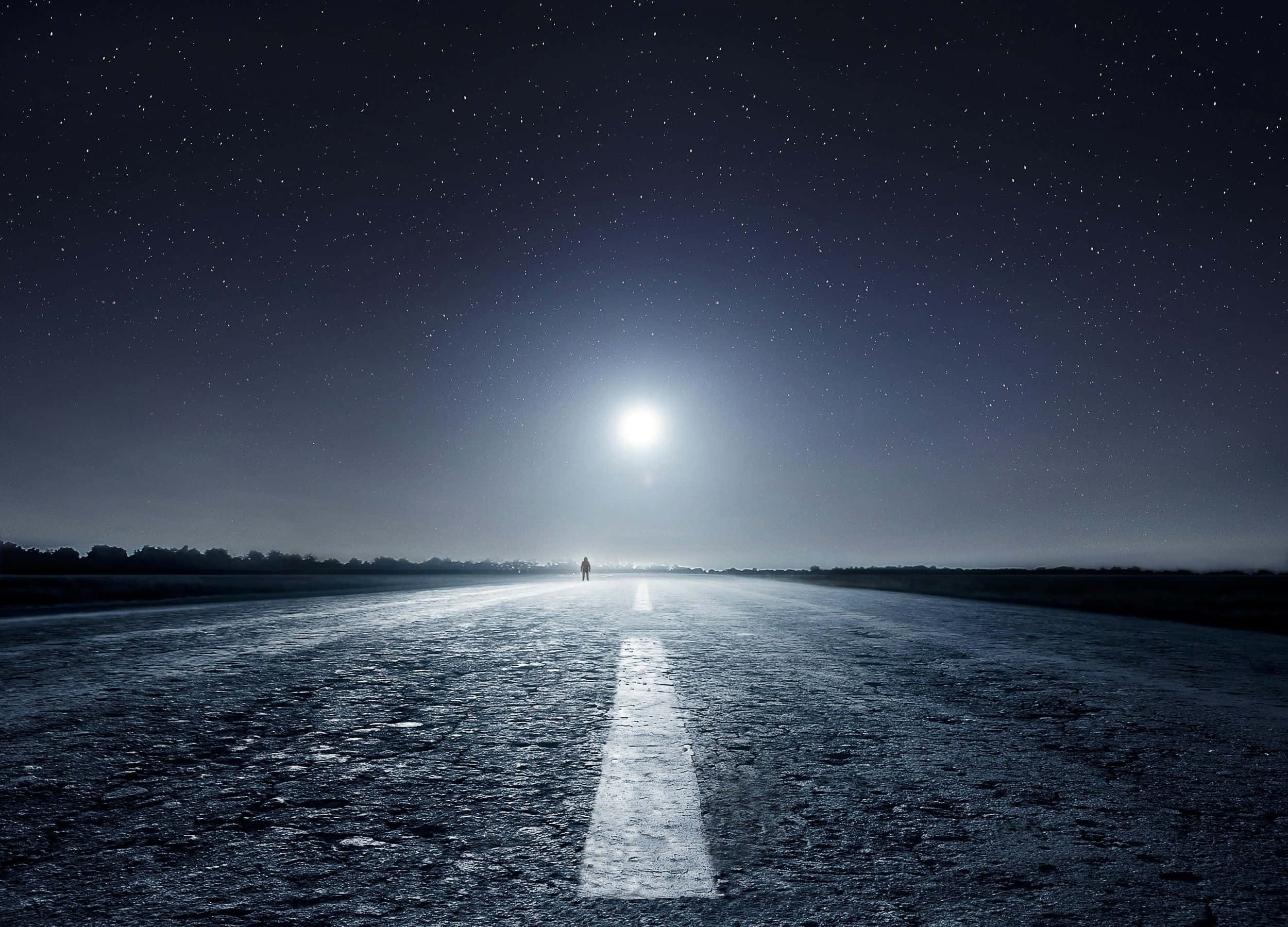 Moonlight 桌布 壁紙 — 一個孤獨的身影在月光照耀的道路上行走，頭上是繁星點點的夜空，前方是一輪明亮的滿月。