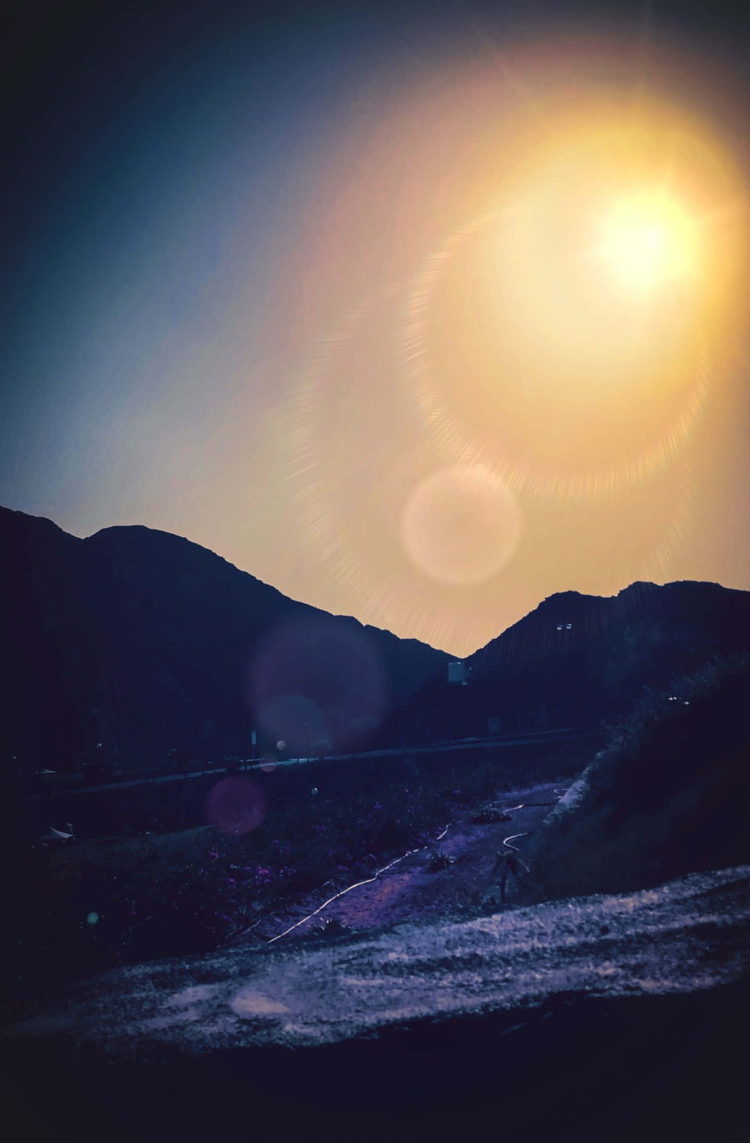 1488x2266 桌布 壁紙 — 一個孤獨的身影在蜿蜒的山路上行走，燦爛的陽光在黑暗的山峰剪影上投射出鏡頭光暈。