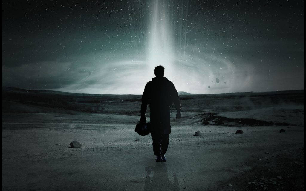Astronaut In Space 桌布 壁紙 — 一個孤獨的身影在黑暗的天空下，走向星際外星景觀中一個發光的宇宙傳送門。