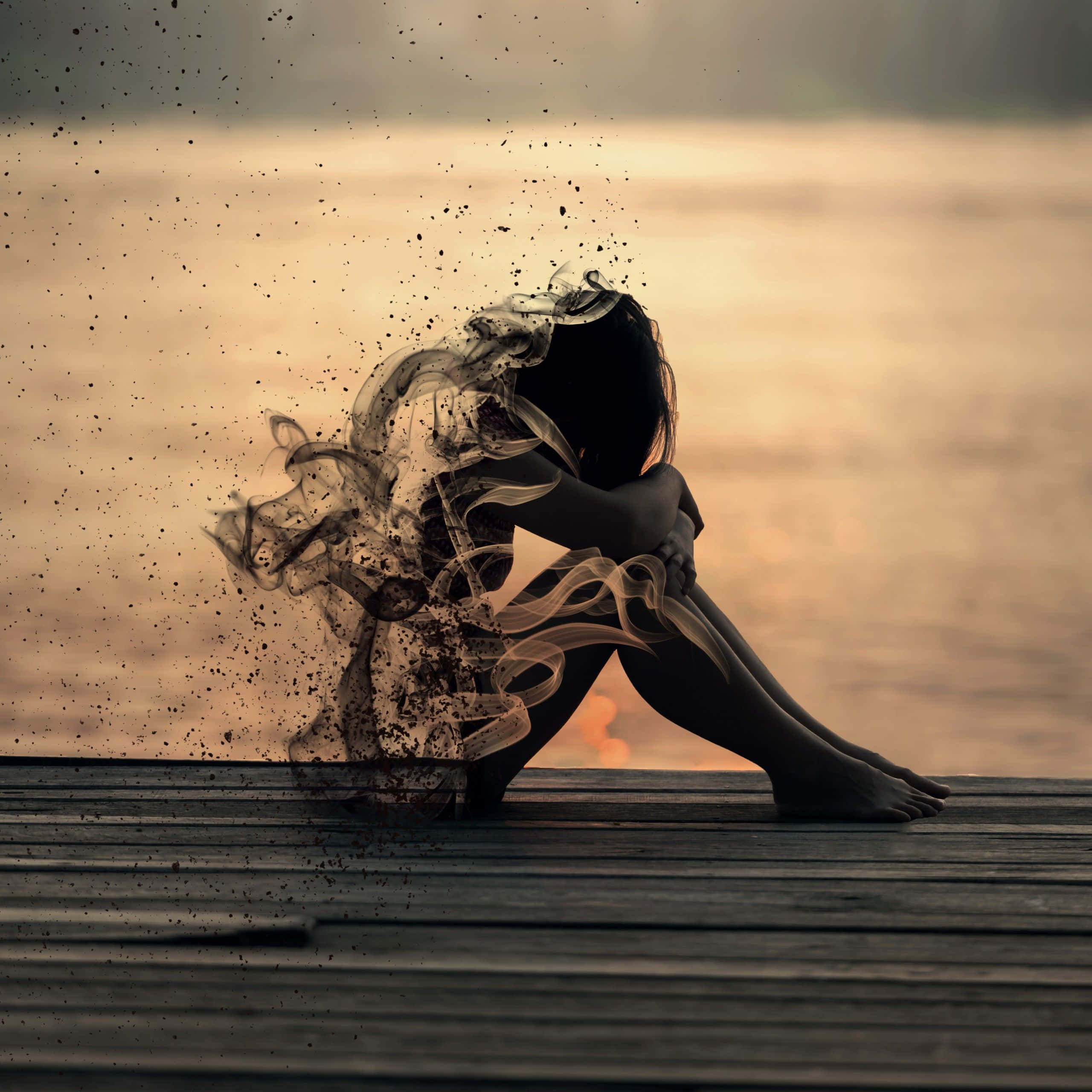 Sad Girl 桌布 壁紙 — 一個孤獨的身影坐在日落時分的木碼頭上，上半身化作旋轉的煙霧，背景是溫暖發光的水面。