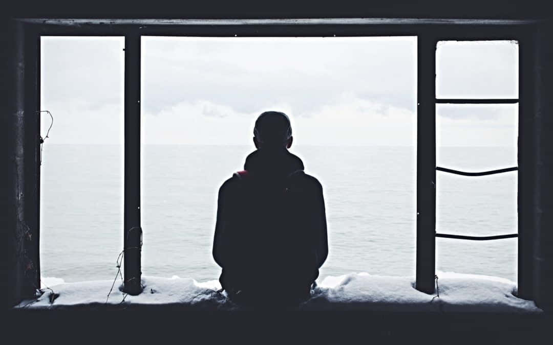 Lonely 桌布 壁紙 — 一個孤獨的身影坐在積雪的窗台上，凝視著陰天下一片廣闊的灰色海洋。