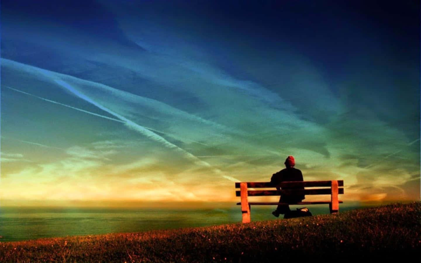Alone 桌布 壁紙 — 一個孤獨的身影戴著紅帽，坐在木長椅上，俯瞰夕陽下廣闊的海洋，天空有條紋狀的雲彩。