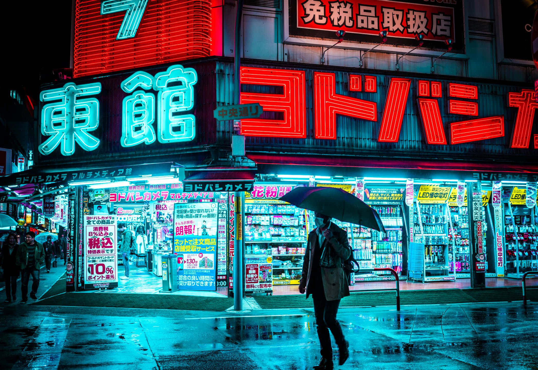 日本 桌布 壁紙 — 一個孤獨的身影撐著傘，在夜晚的東京雨街上行走，被鮮豔的霓虹招牌和發光的商店櫥窗照亮。