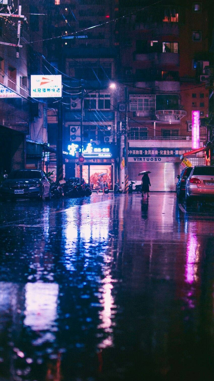 Raining 桌布 壁紙 — 一個孤獨的身影撐著傘，在夜晚雨濕的霓虹燈城市街道上行走，水坑中反射出鮮豔的燈光。