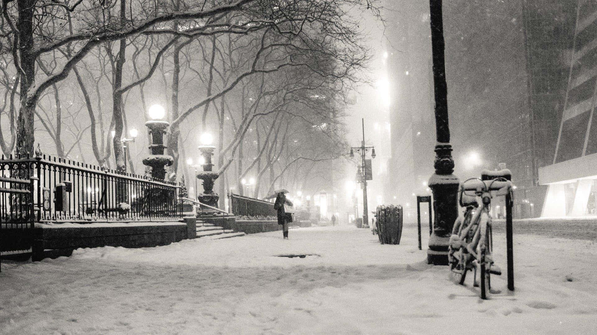 Old Winter 桌布 壁紙 — 一個孤獨的身影撐著傘，沿著一條被白雪覆蓋、兩旁種滿光禿樹木和閃爍街燈的城市人行道行走。