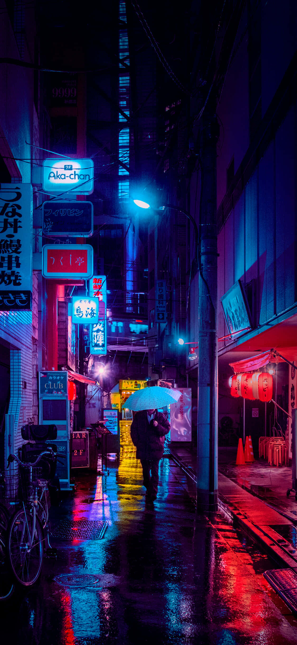 Red Light District 桌布 壁紙 — 一個孤獨的身影撐著傘，走在霓虹燈照亮、雨水浸濕的東京小巷中，反射出鮮豔的紅、藍、紫光。