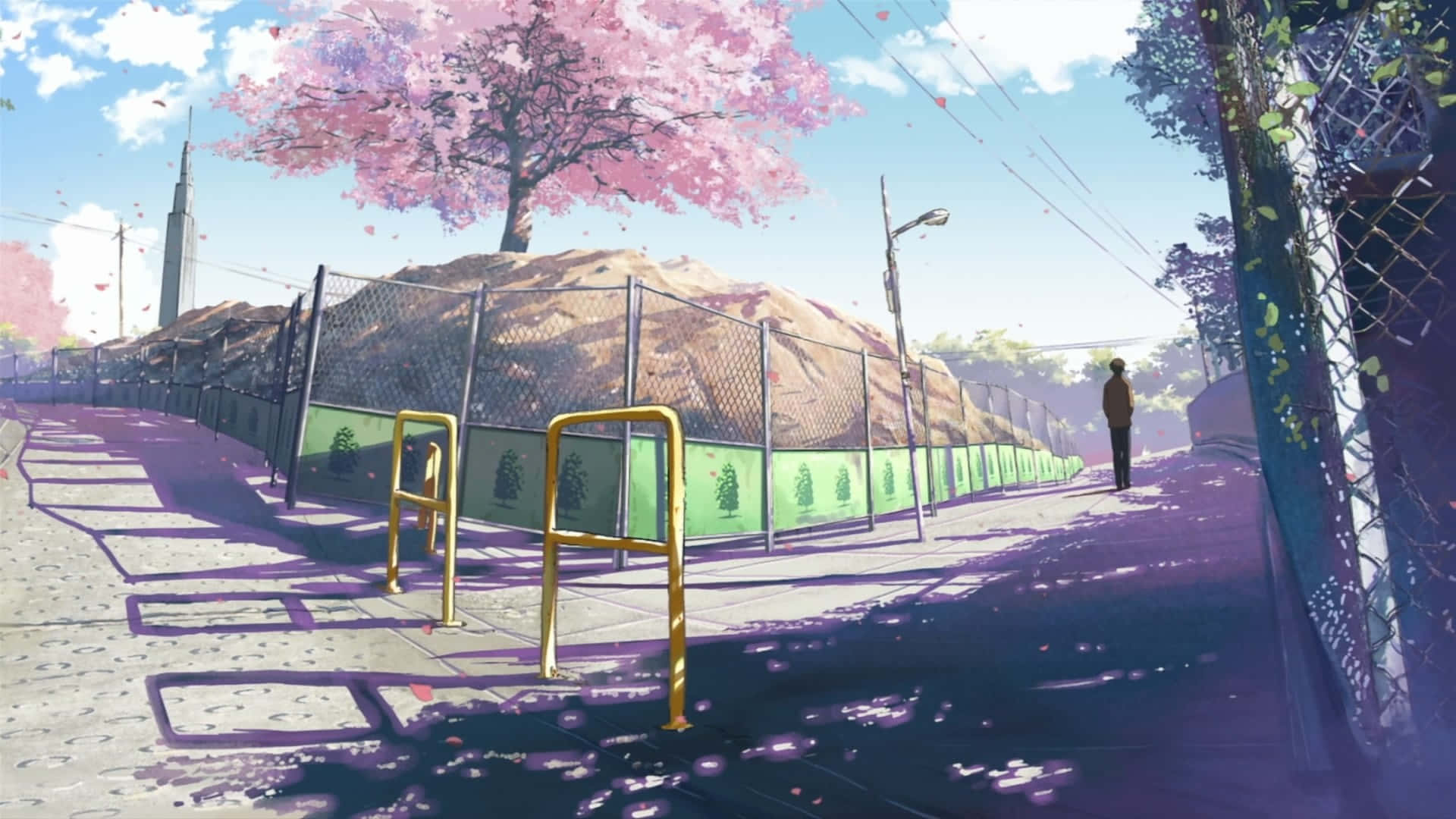 Aesthetic Anime City 桌布 壁紙 — 一個孤獨的身影沿著有圍欄的人行道，在盛開的粉紅色櫻花樹下行走，花瓣飄落，遠處有一座塔。