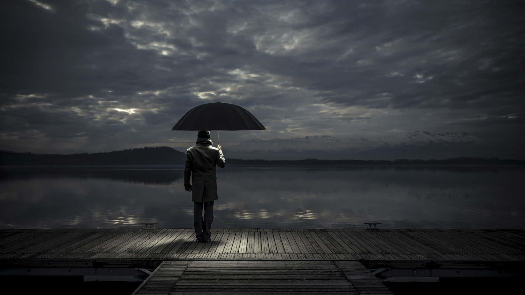 Alone 桌布 壁紙 — 一個孤獨的身影穿著風衣，在木製碼頭上撐著傘，俯瞰著霧氣瀰漫的湖泊，天空灰暗風雨欲來。