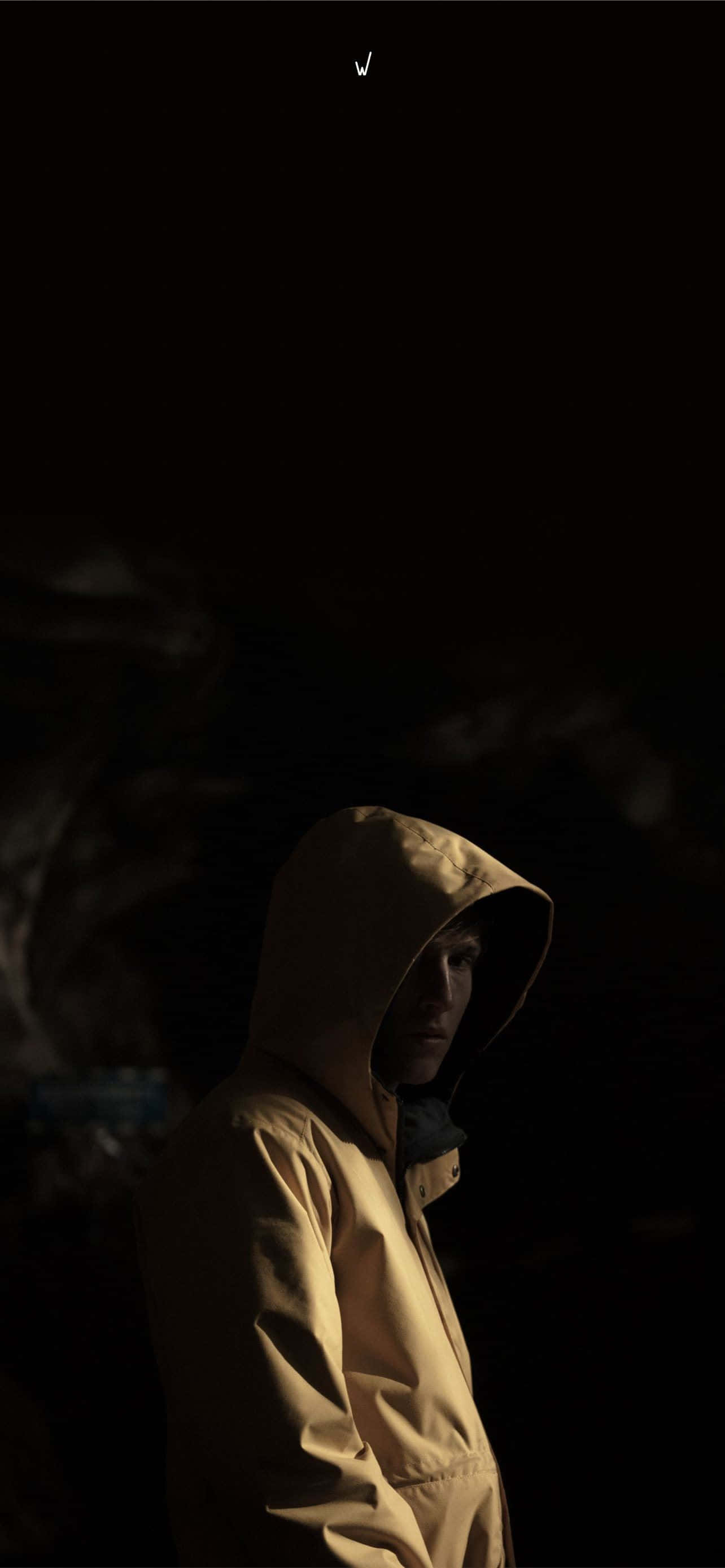 Raincoat 桌布 壁紙 — 一個孤獨的身影穿著黃色連帽外套，站在近乎黑暗的環境中，戲劇性的側光突出了他們的臉和外套。