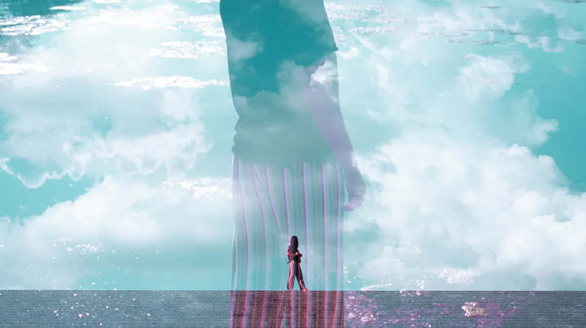 Dreaming 桌布 壁紙 — 一個孤獨的身影站在一個從水上多雲的藍綠色天空中出現的巨大半透明人形剪影前。