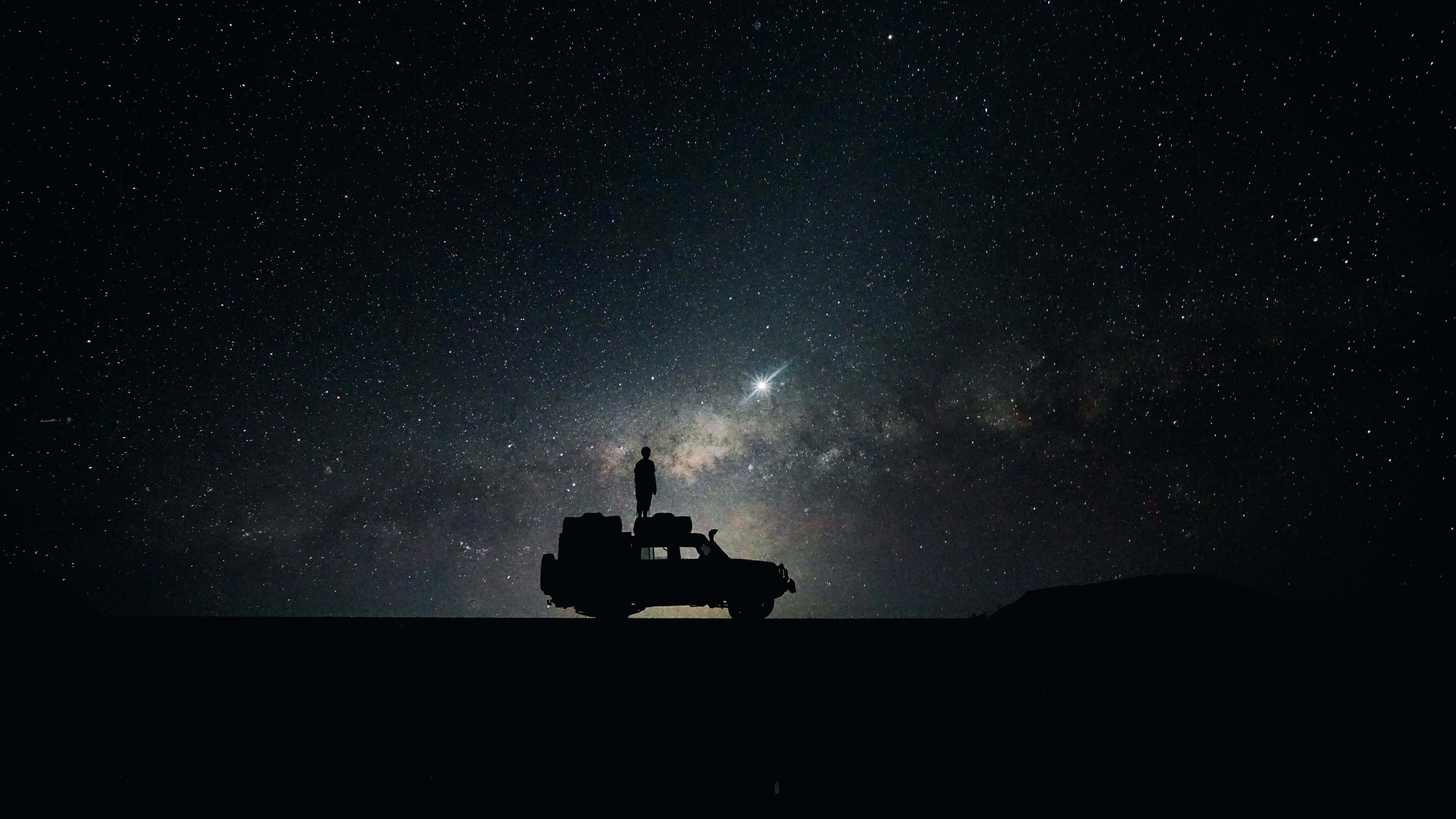 Beautiful Space 桌布 壁紙 — 一個孤獨的身影站在堅固的車輛上，頭頂上是令人嘆為觀止的星空，銀河在閃耀。