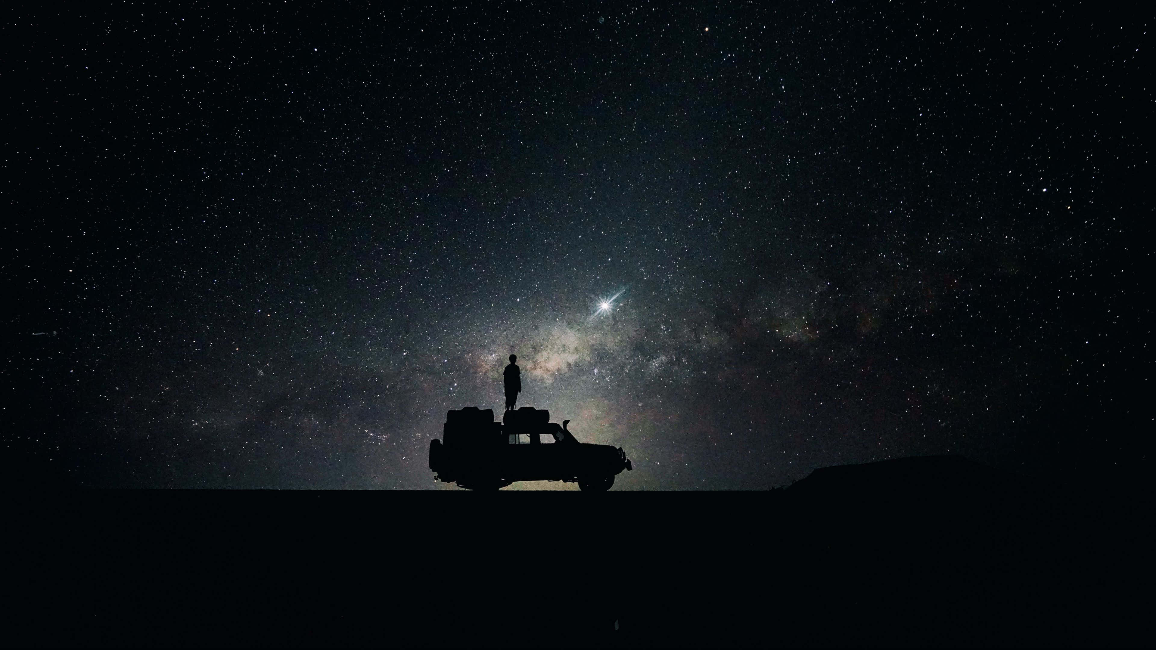 Starry 桌布 壁紙 — 一個孤獨的身影站在堅固的車輛上，頭頂上是令人屏息的星空，銀河閃耀。