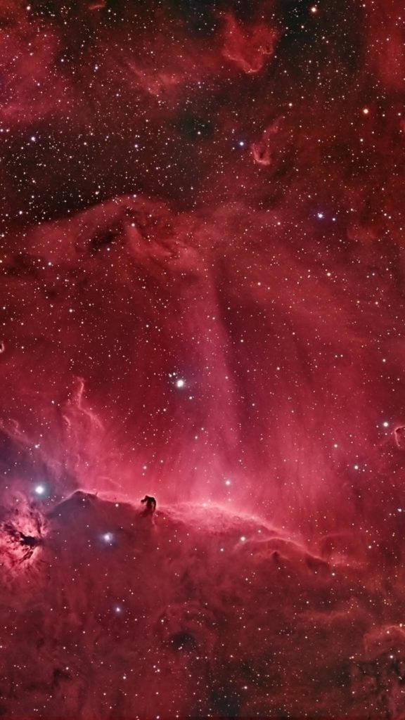 iPhone 8 red 桌布 壁紙 — 一個孤獨的身影站在宇宙山丘之巔，下方是廣闊的紅色星雲，閃爍著星光。