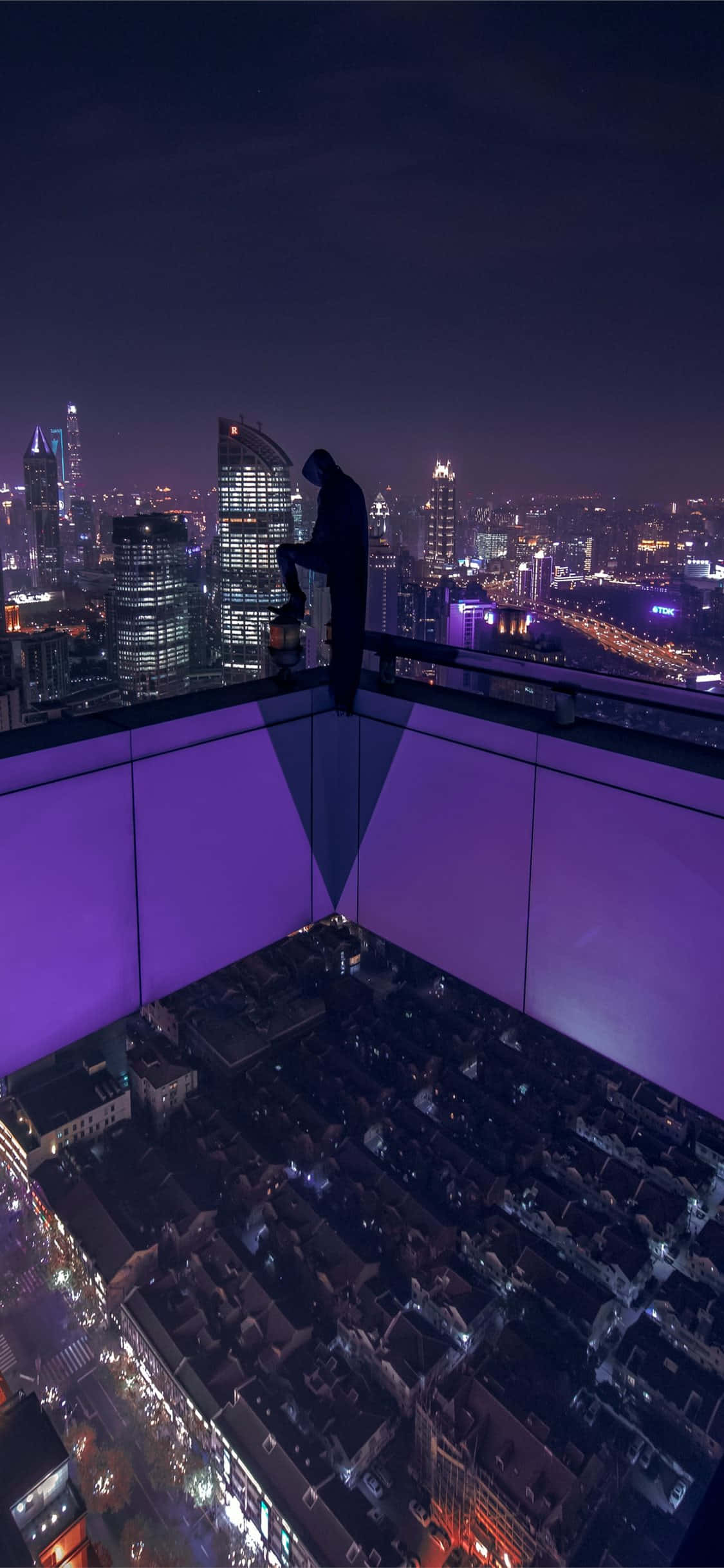 Rooftop 桌布 壁紙 — 一個孤獨的身影站在屋頂上，俯瞰著夜晚充滿活力的霓虹燈城市景觀，帶有紫色環境燈光。