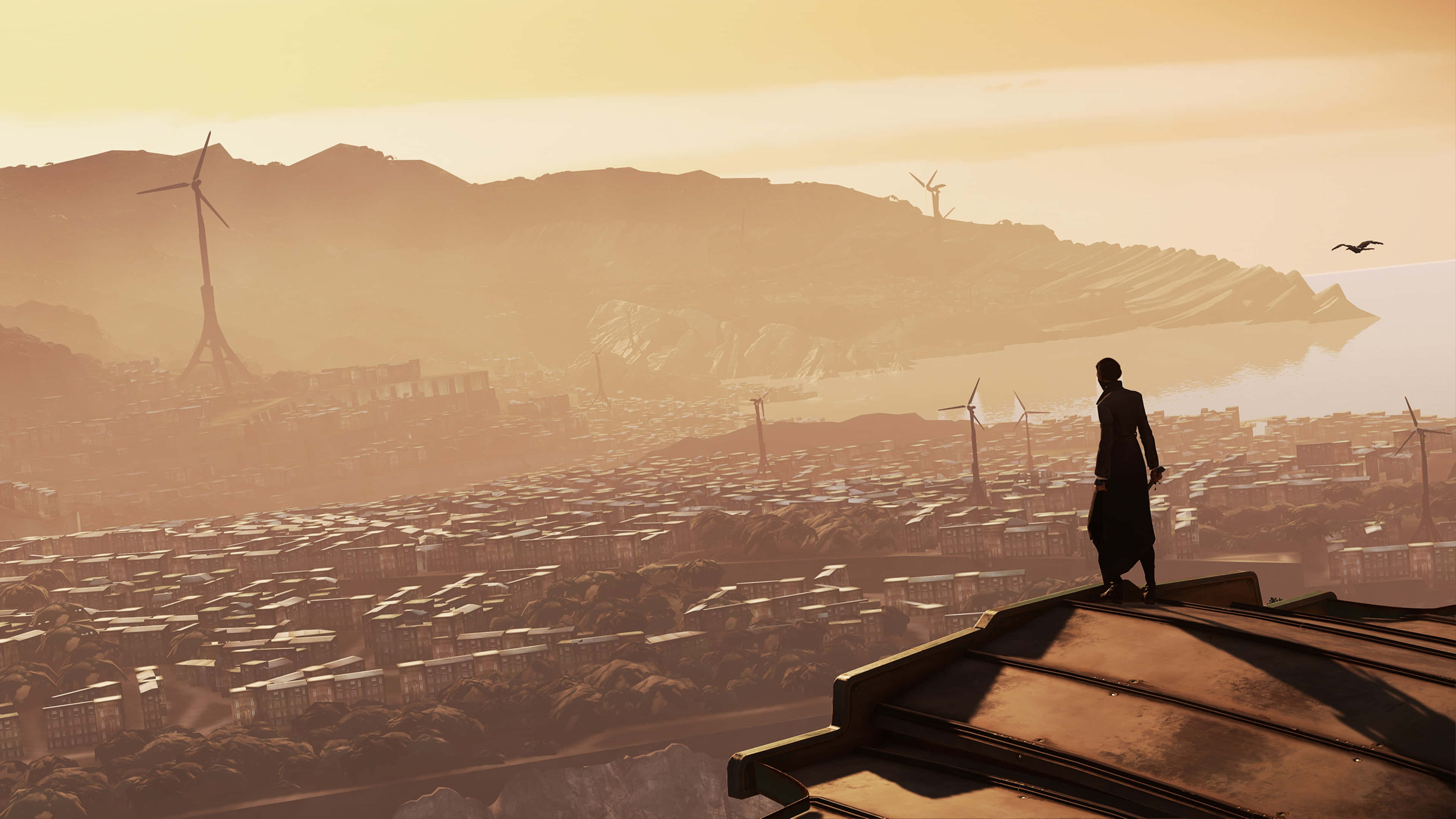冤罪殺機 桌布 壁紙 — 一個孤獨的身影站在屋頂上，俯瞰著沐浴在金色日落光芒中的廣闊城市景觀，遠處的山丘上點綴著風力發電機。