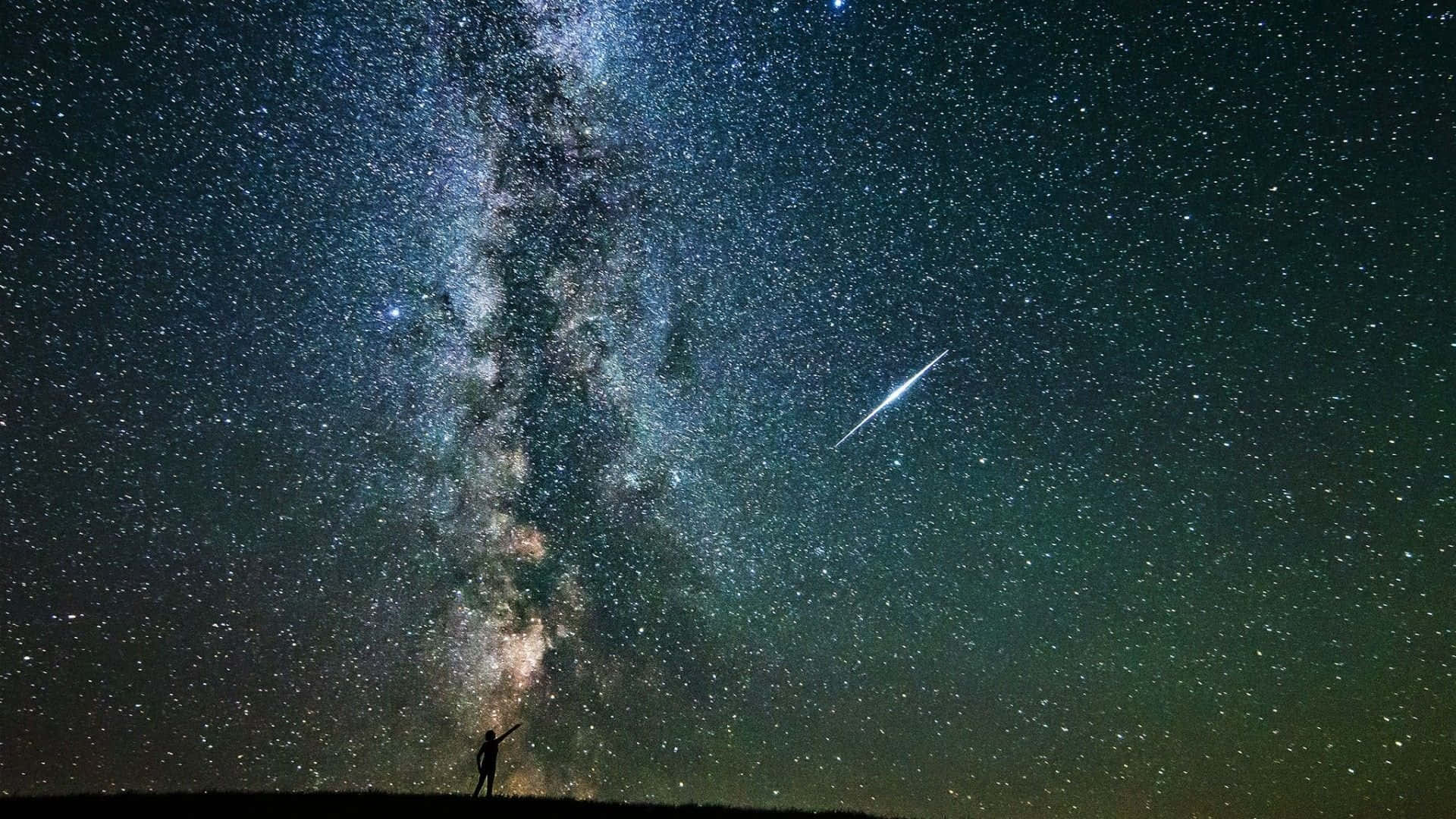 Stars 桌布 壁紙 — 一個孤獨的身影站在山丘上，仰望銀河系，一顆明亮的流星劃過繁星點點的夜空。