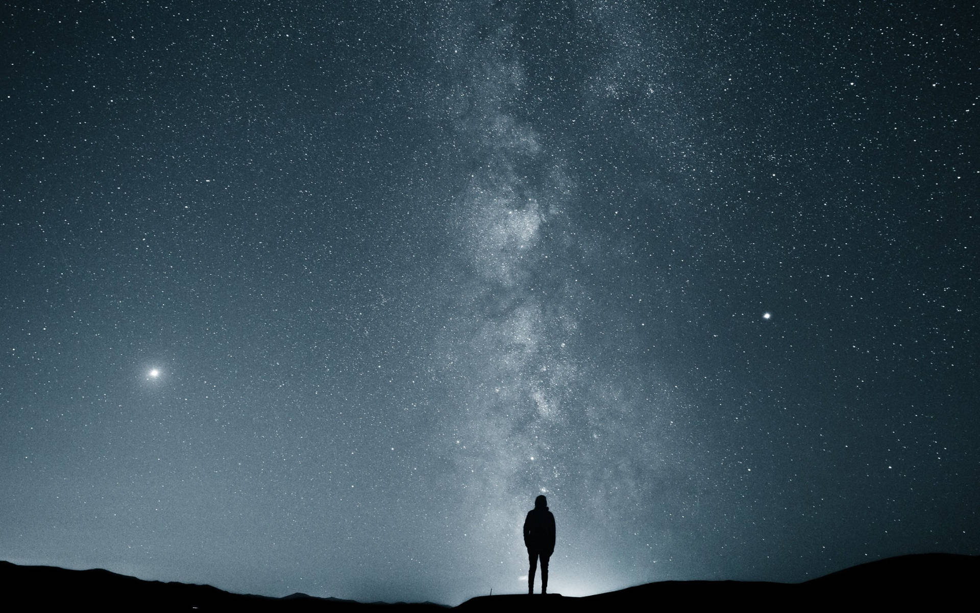 Alone 桌布 壁紙 — 一個孤獨的身影站在山頂上，仰望佈滿銀河的壯麗星空。