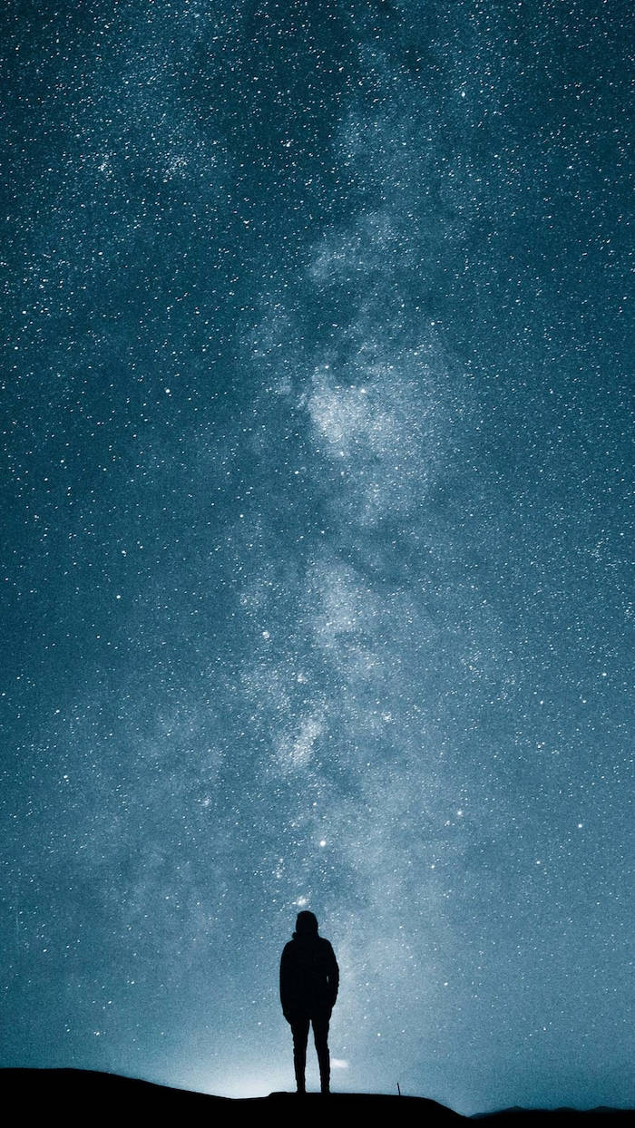 酷炫星系 桌布 壁紙 — 一個孤獨的身影站在山頂上，仰望滿是銀河的壯麗星空。