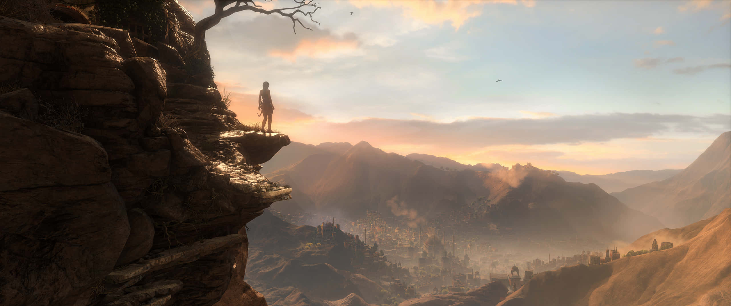 Rise Of The Tomb Raider 桌布 壁紙 — 一個孤獨的身影站在岩石懸崖邊緣，俯瞰著沐浴在金色日落光芒中的廣闊山谷。