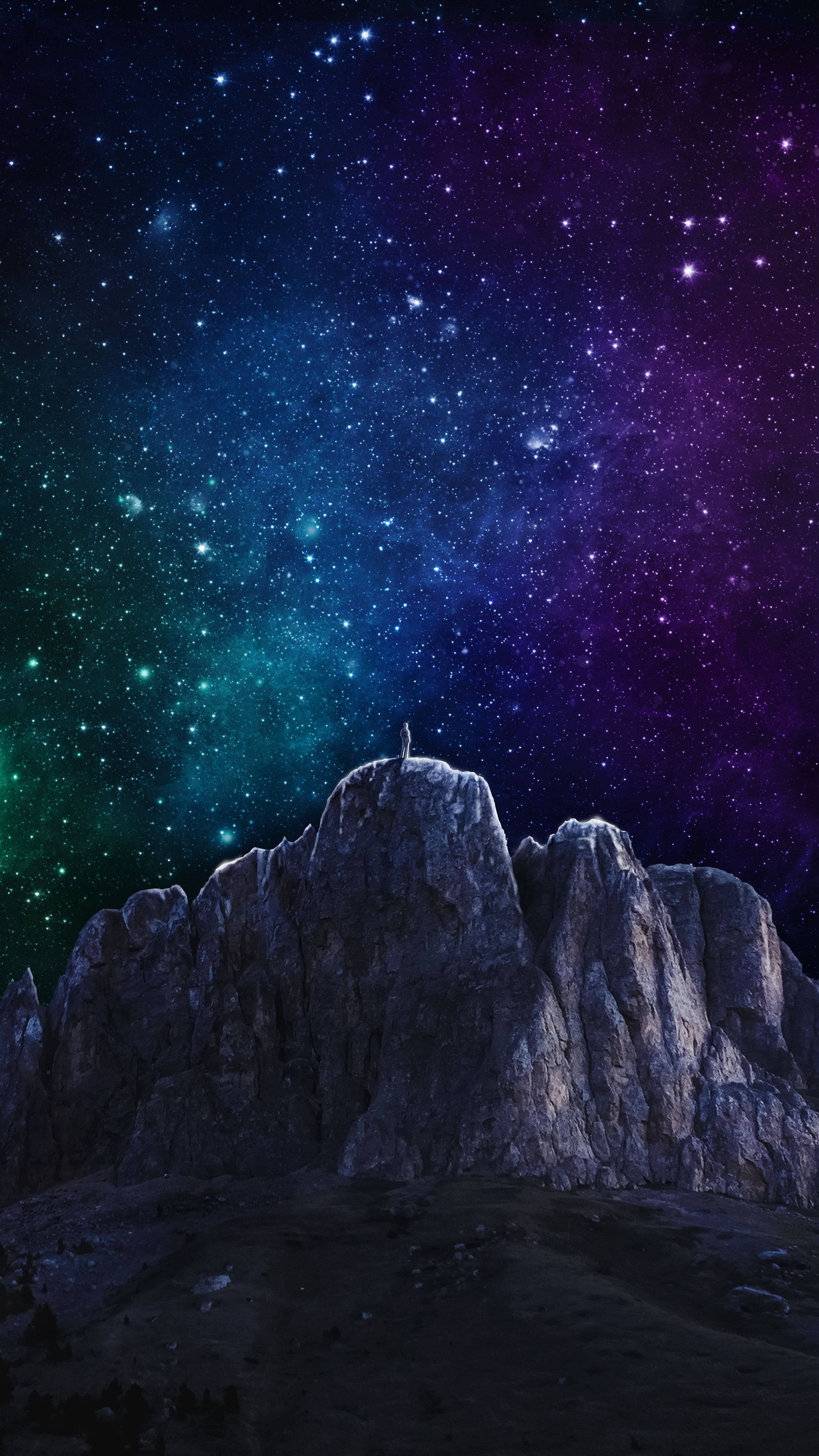 Note 8 桌布 壁紙 — 一個孤獨的身影站在崎嶇的山峰上，頭頂是令人嘆為觀止的宇宙天空，充滿了深藍、紫色和綠色的星星和星雲。
