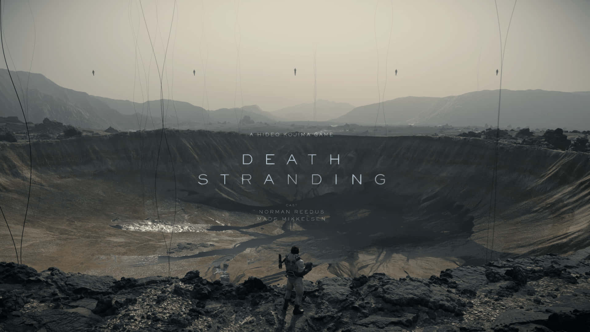 Death Stranding Pc 桌布 壁紙 — 一個孤獨的身影站在廣闊隕石坑的邊緣，在朦朧的天空下，有懸掛的電線和遠山，景觀荒涼。