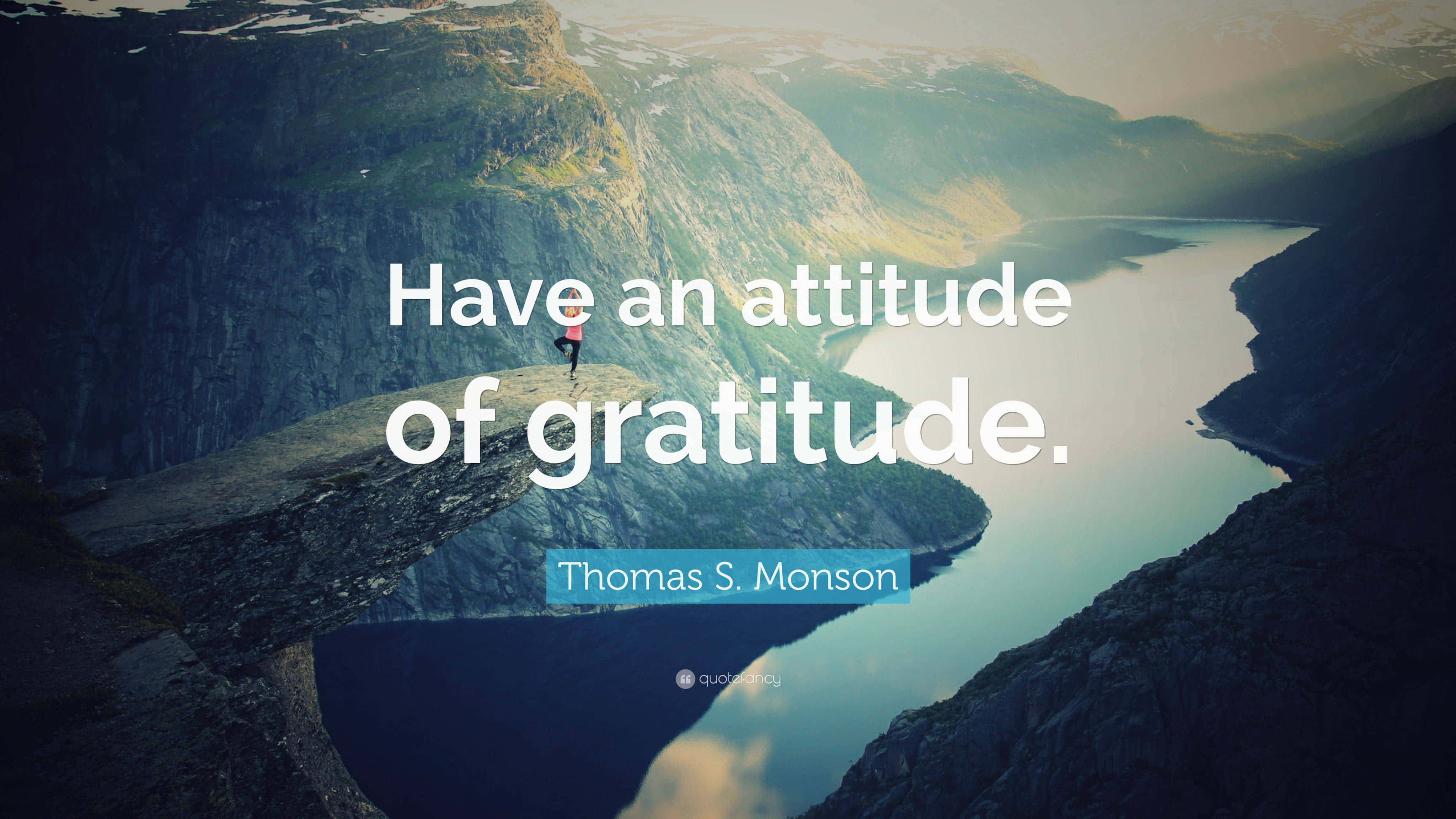 Gratitude 桌布 壁紙 — 一個孤獨的身影站在懸崖邊，俯瞰著在柔和晨光中聳立群山環抱的寧靜峽灣。