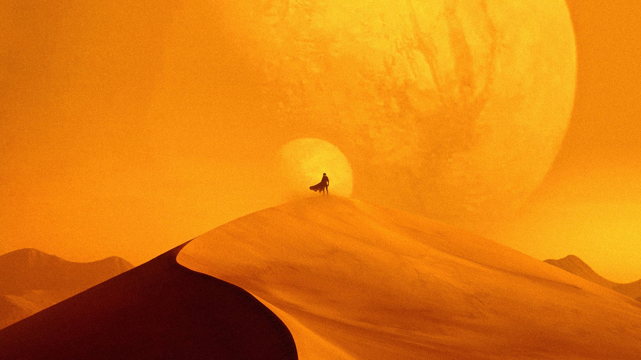 Dune 2021 桌布 壁紙 — 一個孤獨的身影站在沙丘頂端，下方是超現實沙漠景觀中一顆巨大發光的橙色行星。