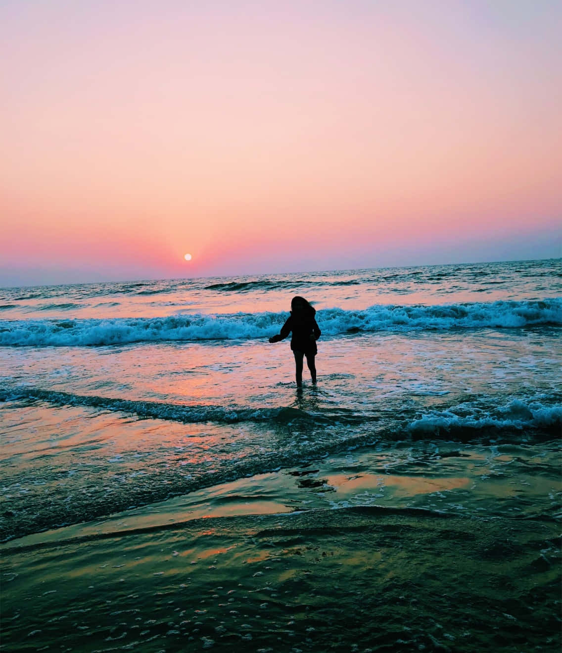 夏日美學動畫 桌布 壁紙 — 一個孤獨的身影站在淺海波浪中，夕陽在粉紅色和橙色的天空漸變中落下。