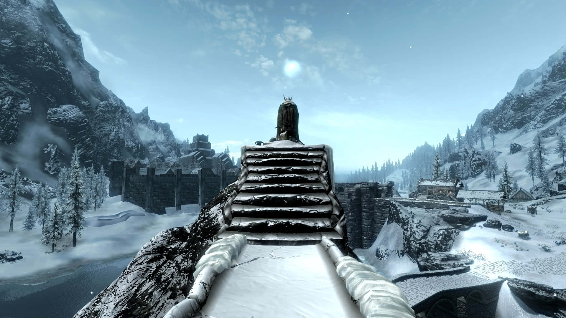 Skyrim Windhelm 桌布 壁紙 — 一個孤獨的身影站在白雪覆蓋的石橋上，俯瞰著蒼白冬日天空下冰封的山村。