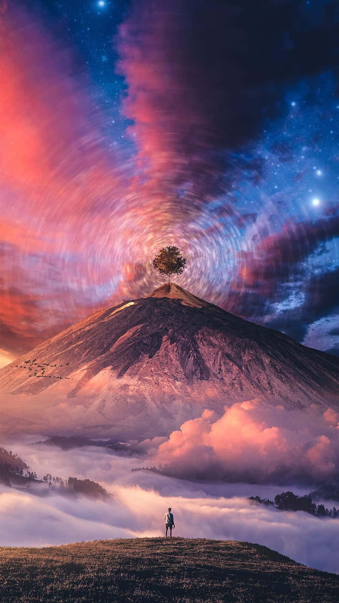 Trippy Sky 桌布 壁紙 — 一個孤獨的身影站在長滿草的山丘上，凝視著一座雄偉的山峰，山頂有一棵孤樹，背景是漩渦般的宇宙天空。