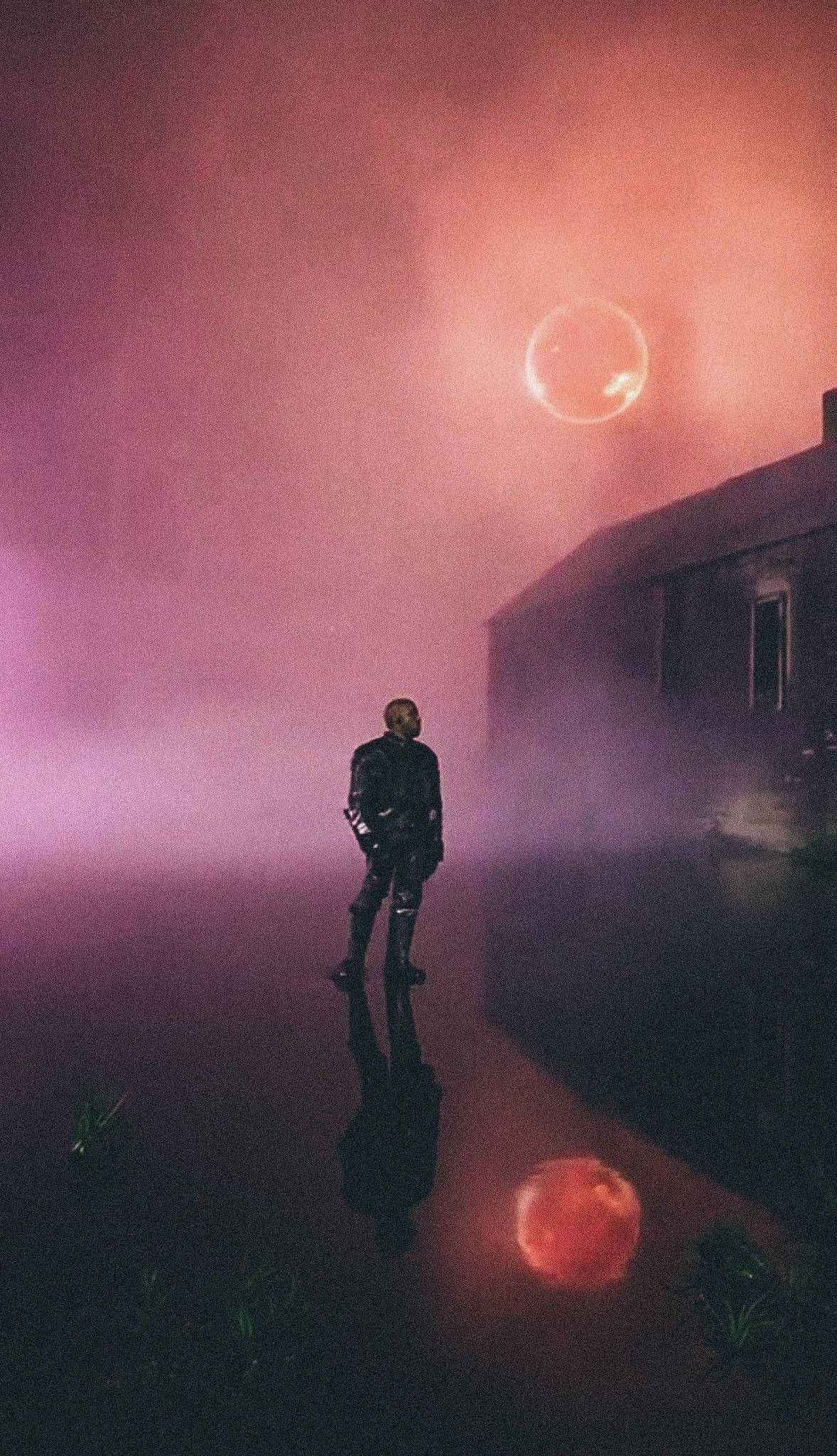 Kanye West Album Cover 桌布 壁紙 — 一個孤獨的身影站在霧氣朦朧的暮色中，旁邊是一座破敗的建築，上方懸浮著一顆發光的粉紅色球體。