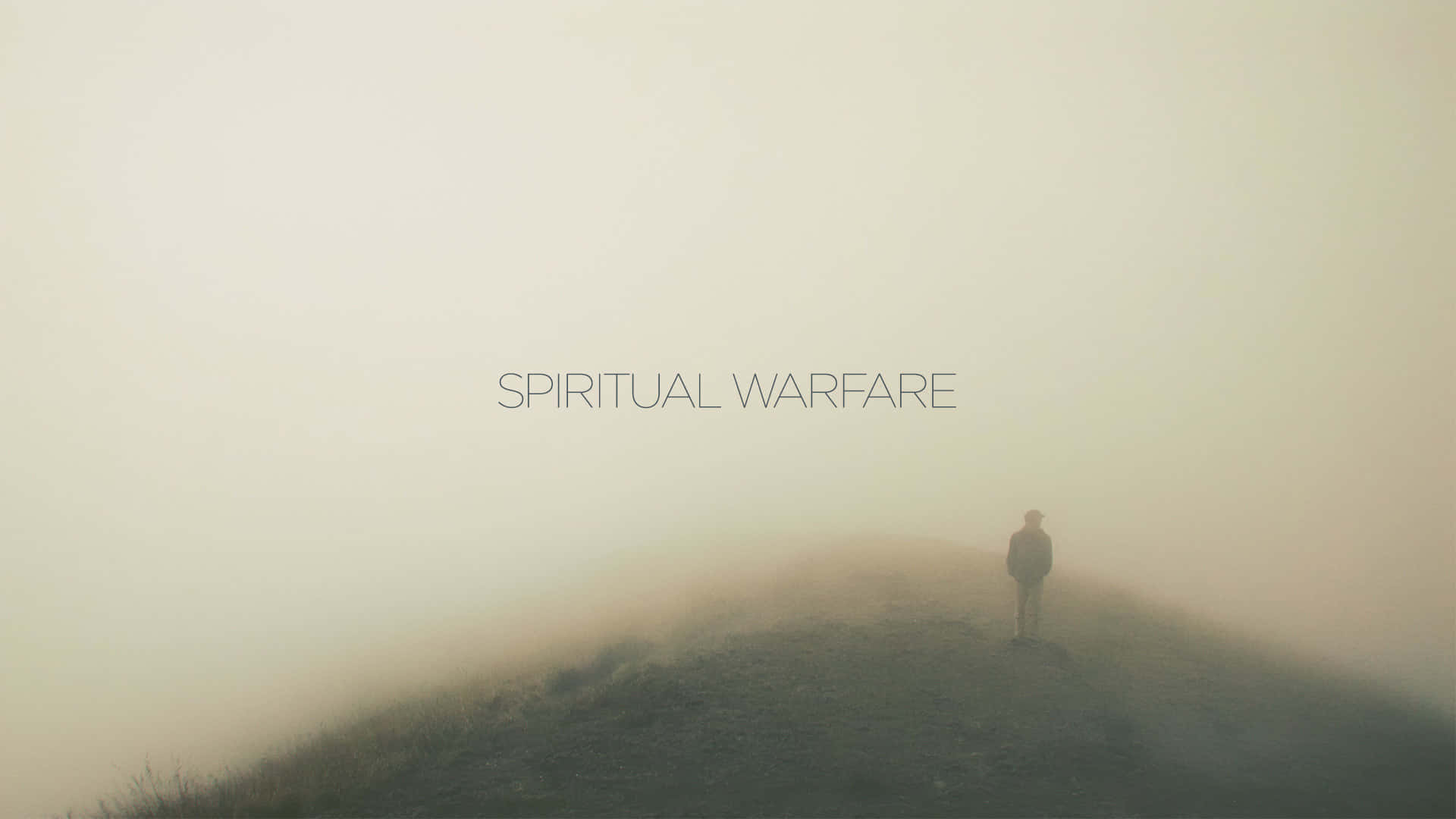桌布 壁紙 — 一個孤獨的身影站在霧氣籠罩的山丘上，天空朦朧，上面覆蓋著 spiritual warfare 的文字。